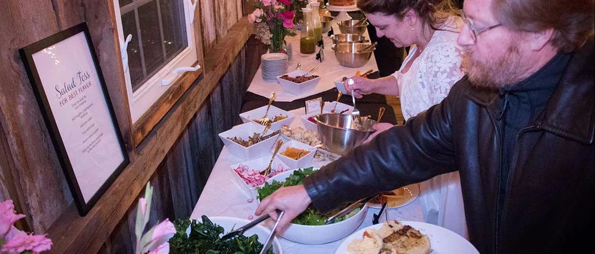 Guests enjoying a salad bar at a rustic event venue