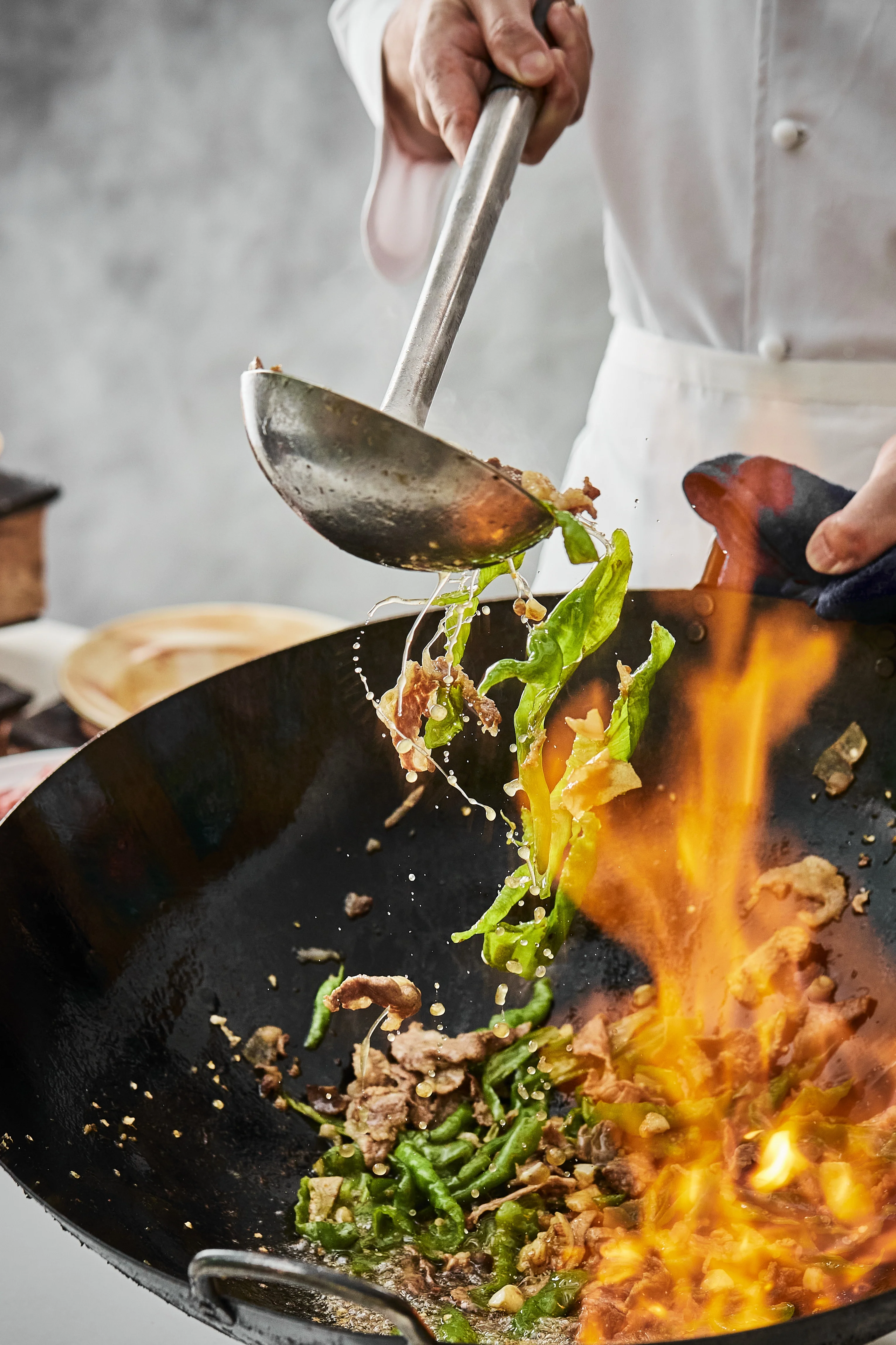 Chef preparing food in a busy kitchen with steam and bamboo steamer.