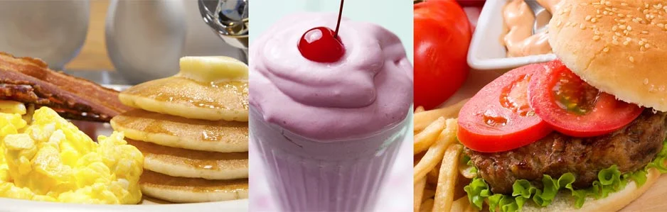 A delicious spread of breakfast and burger foods: scrambled eggs and bacon, a pink dessert with a cherry on top, and a burger with lettuce and tomato served with fries.