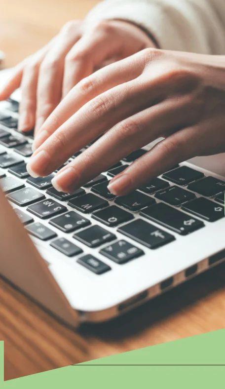 Hands typing on a laptop keyboard in a cozy setting