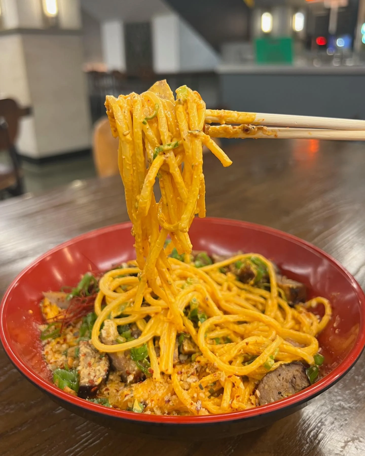 Spicy Thai noodles with vegetables in a red bowl
