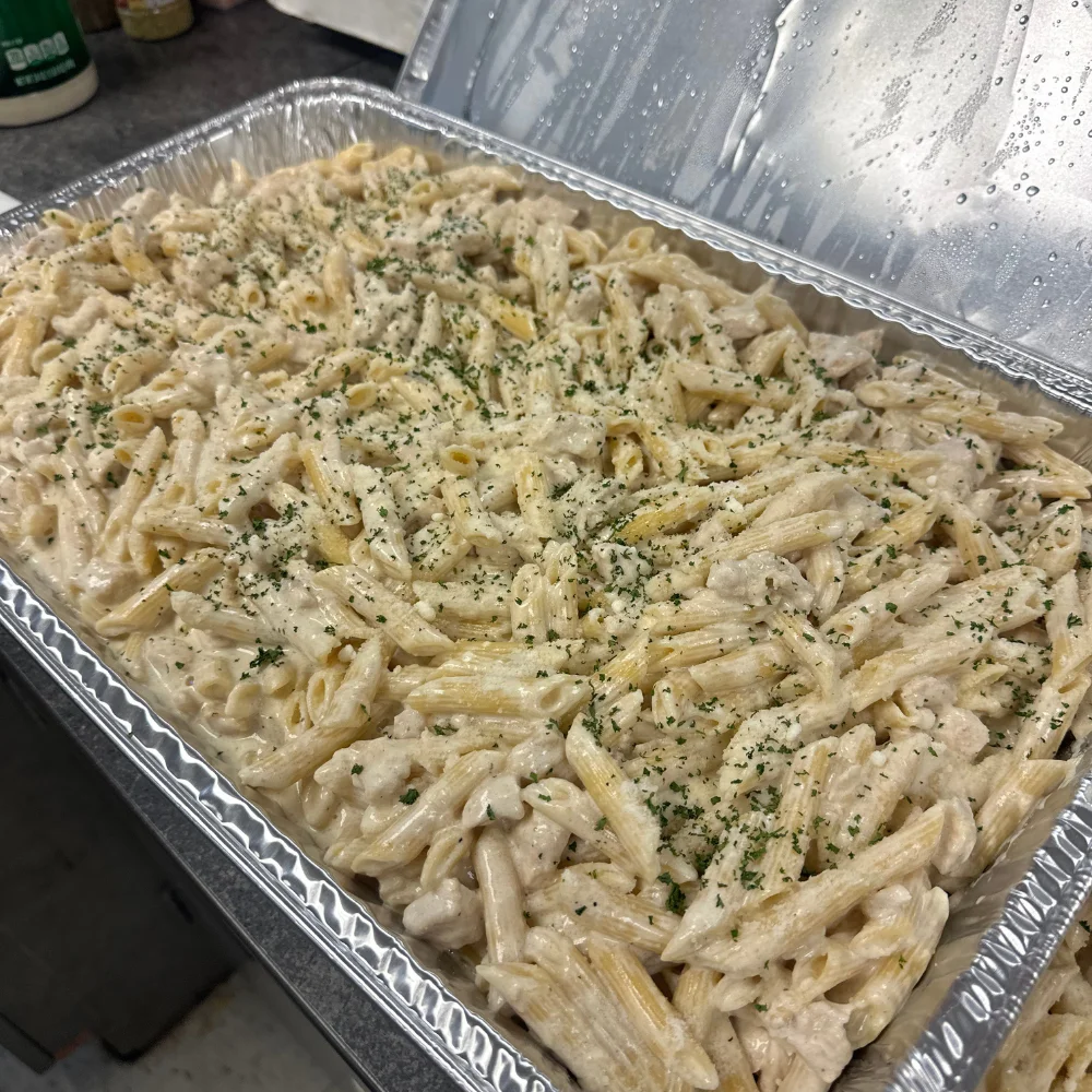 Creamy chicken penne pasta bake in a catering tray