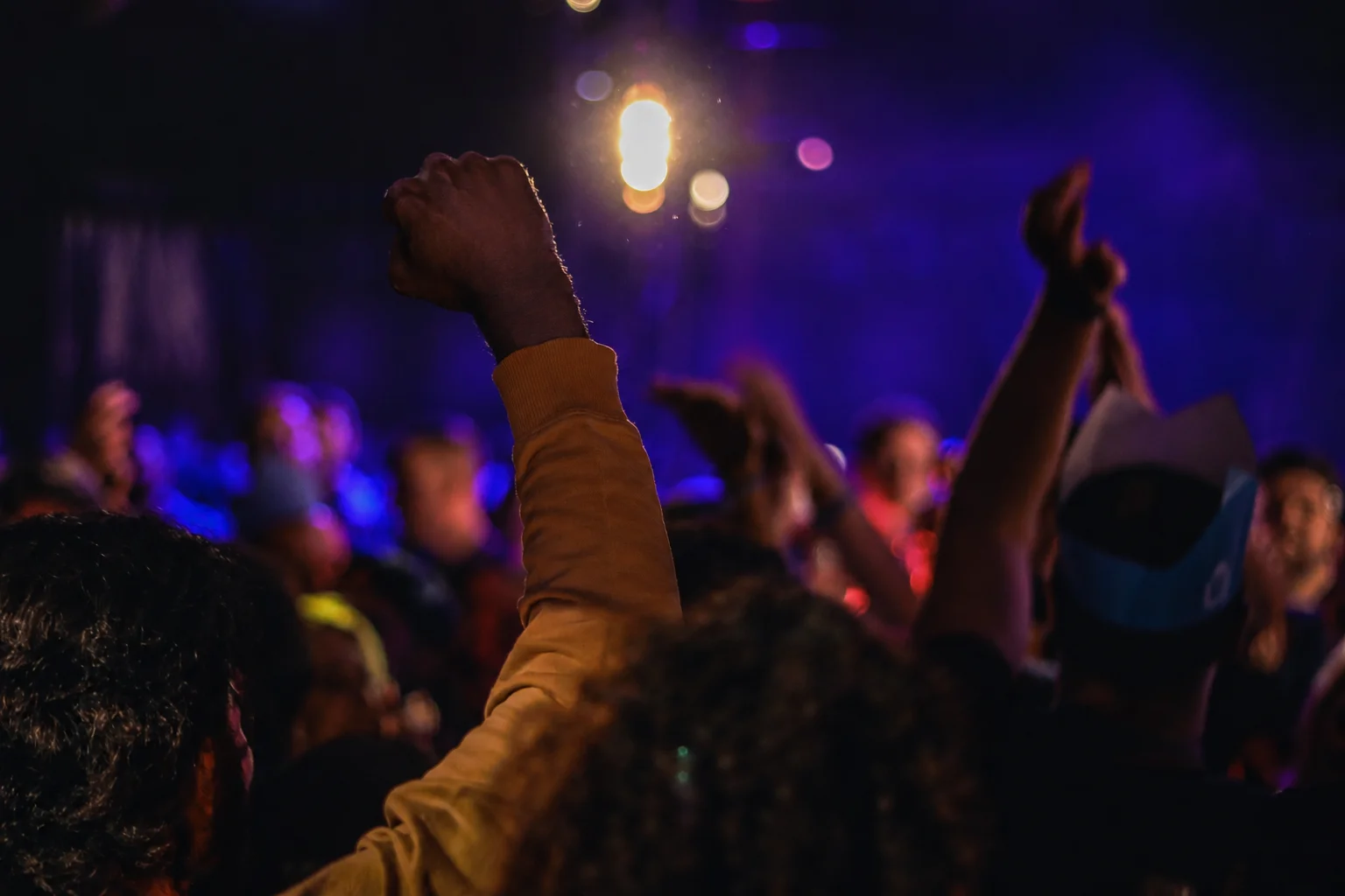 Crowd cheering with raised hands at a lively event
