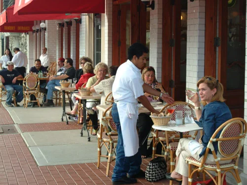 Outdoor dining scene at a bustling restaurant with patrons enjoying their meals