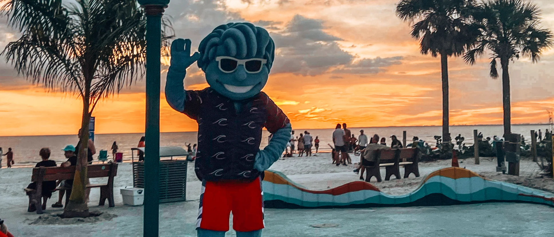 Colorful mascot waving at sunset on the beach