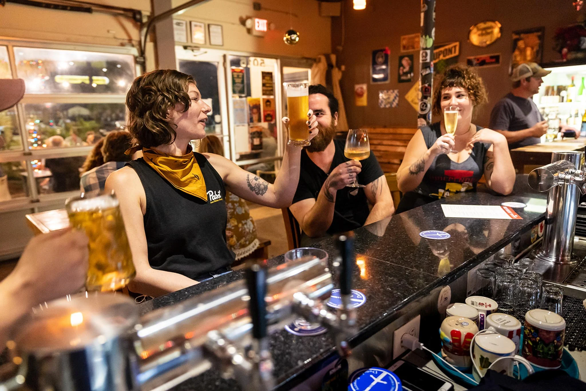 Group of friends toasting with drinks at a lively bar counter