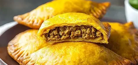 Golden-brown empanadas filled with seasoned meat on a plate.
