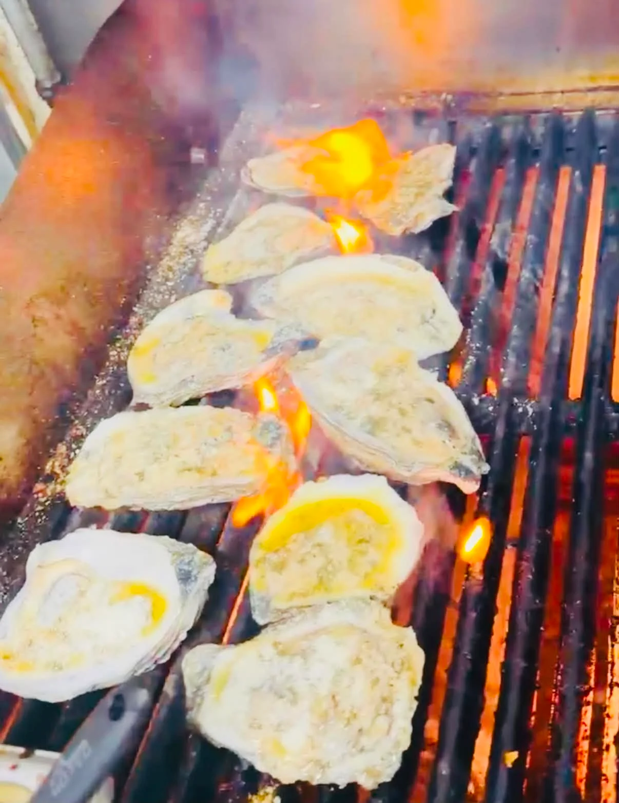 Grilled oysters on a barbecue with flames and smoke