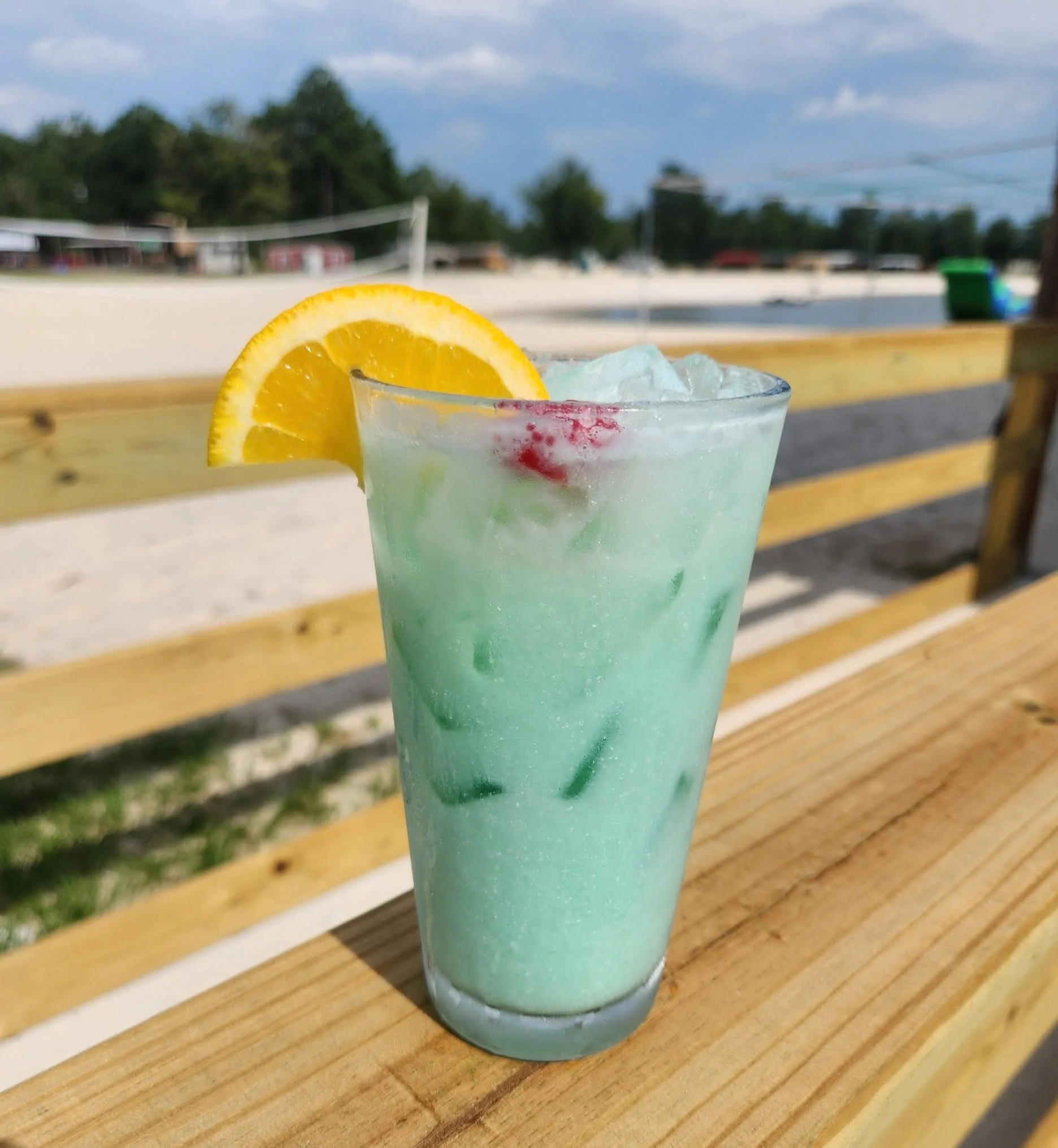Refreshing blue cocktail with lemon and cherry garnish