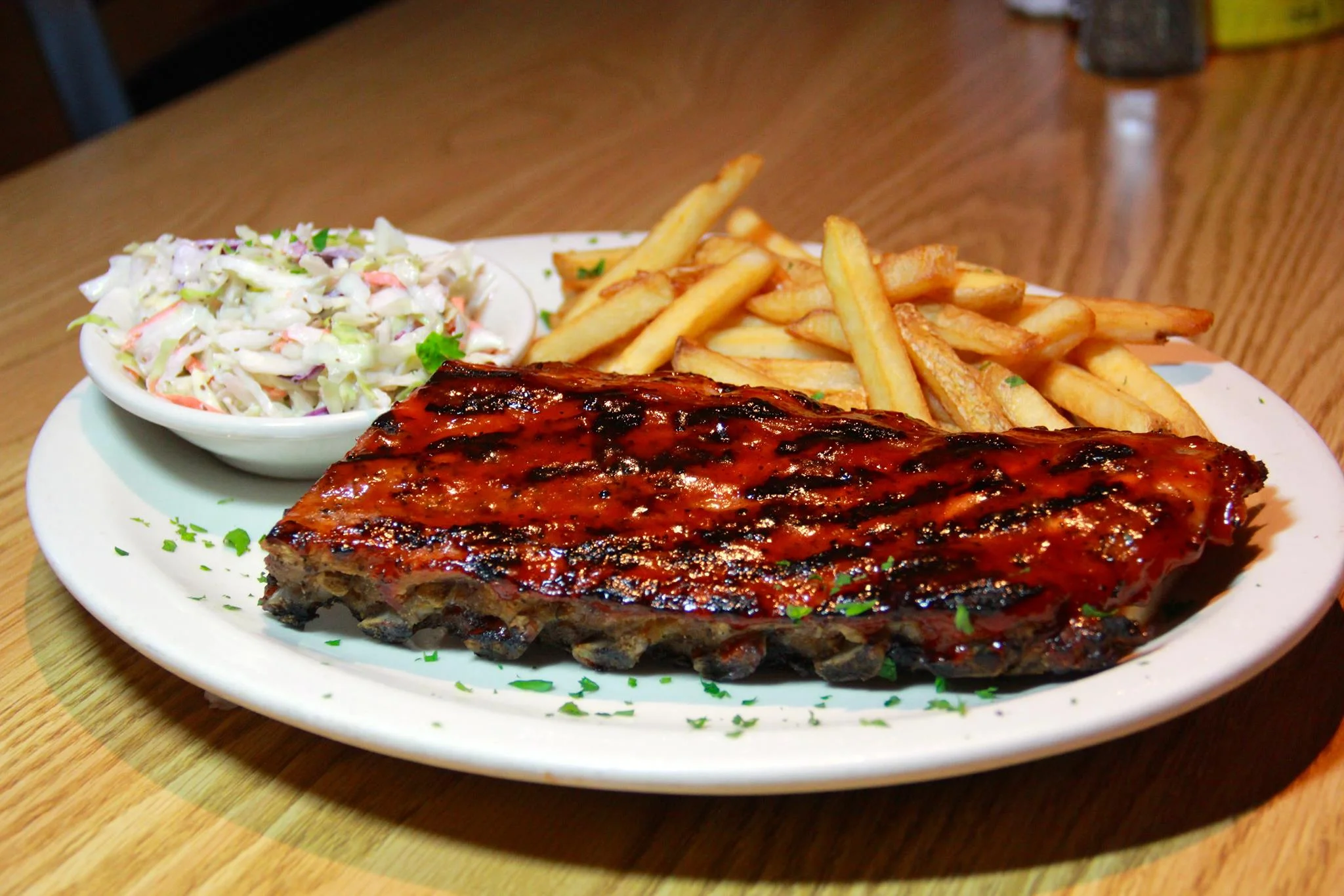 BBQ ribs served with coleslaw and French fries in a casual dining setting