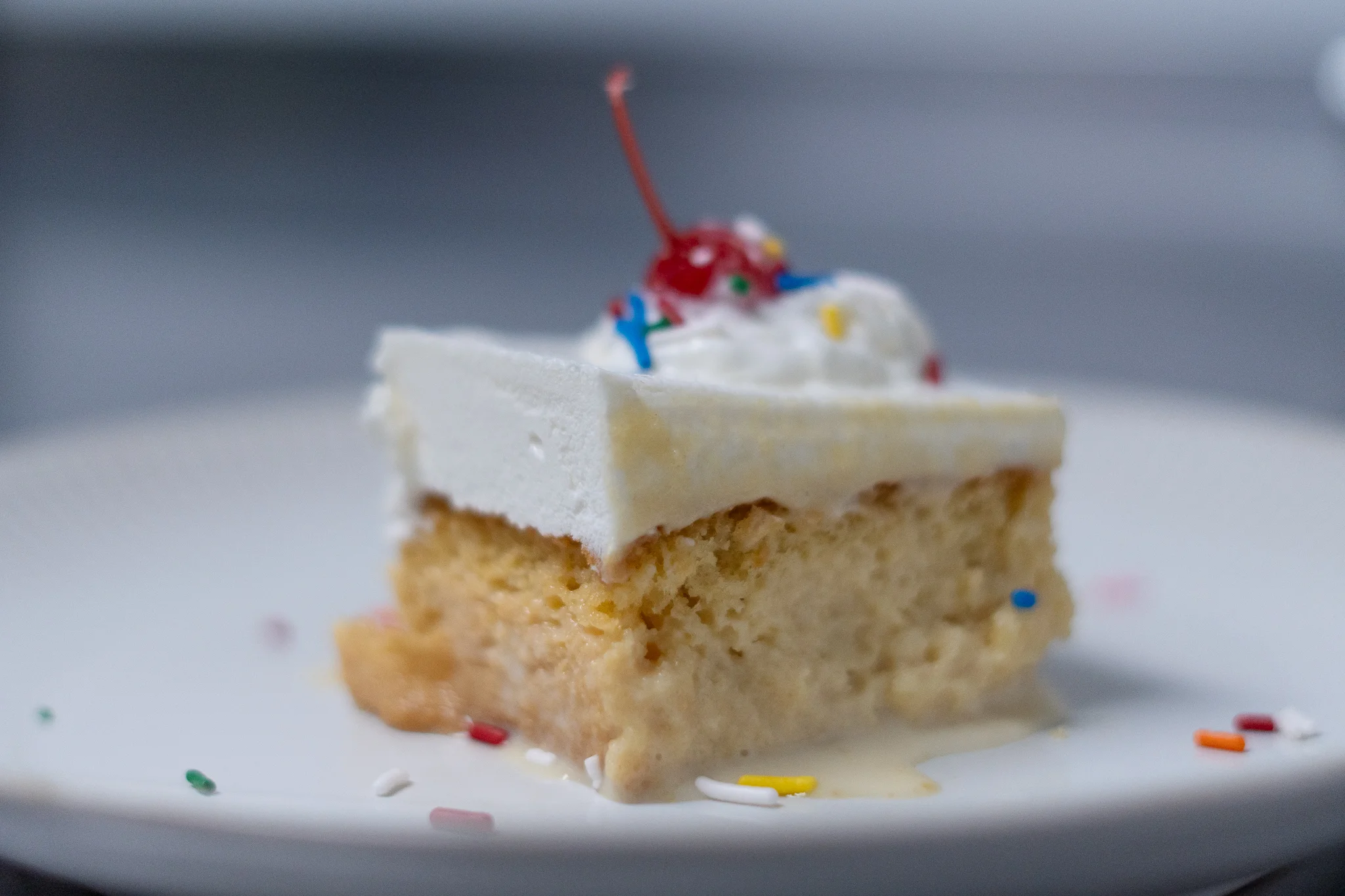 Slice of classic American cake topped with whipped cream and cherry