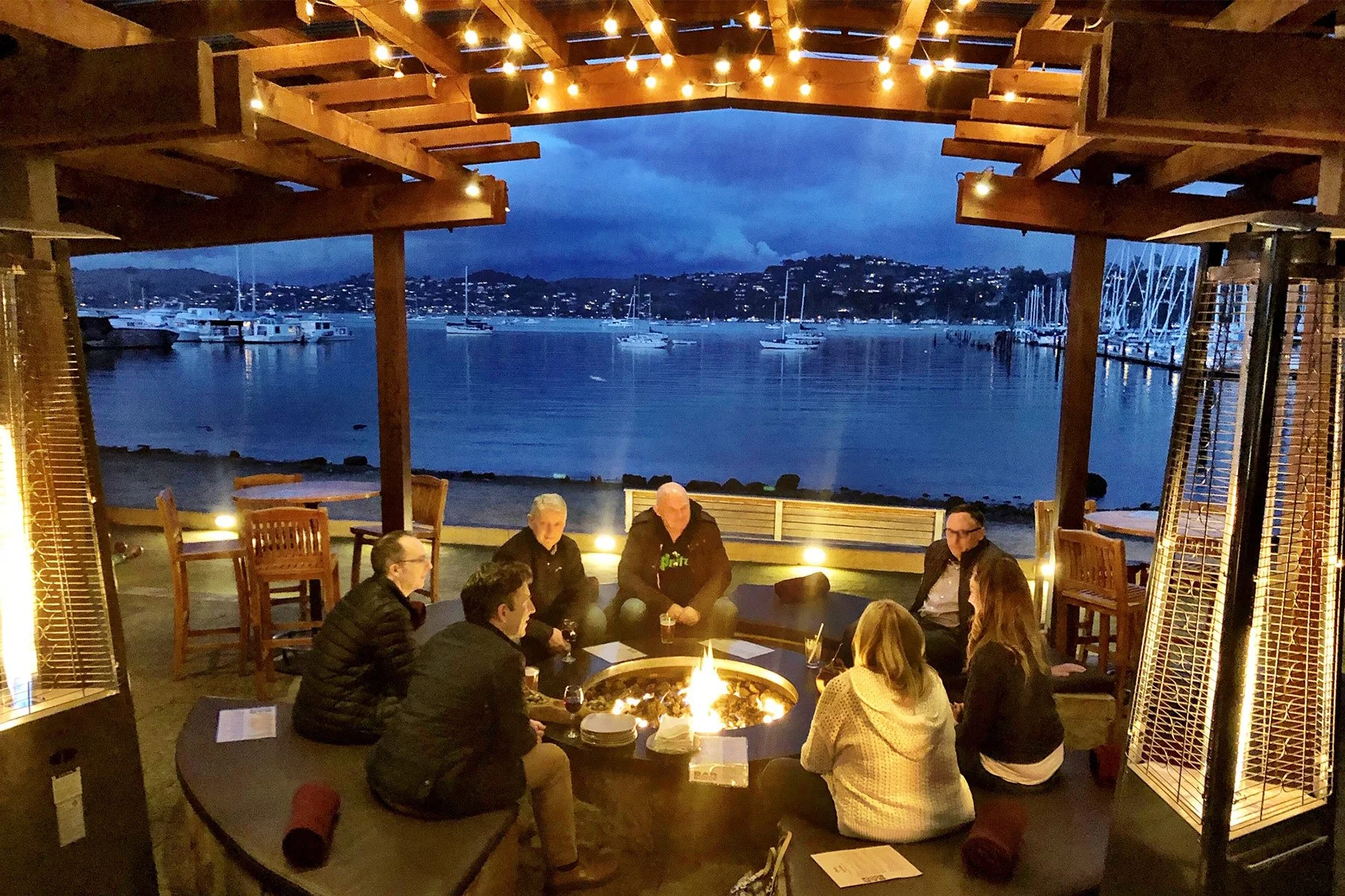people sitting around a Bar bocce fire pit at night