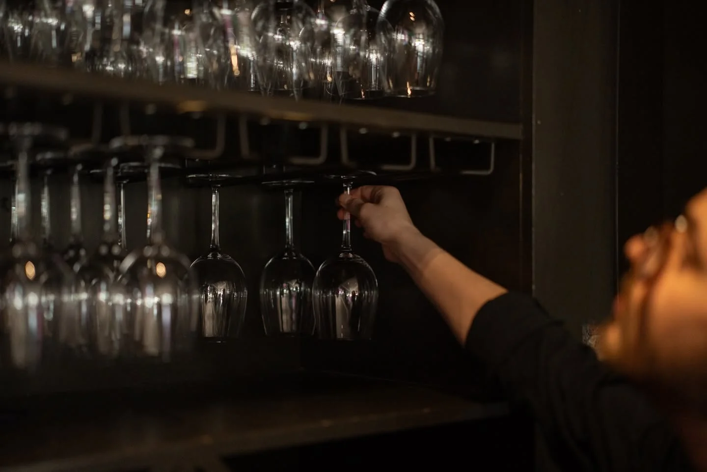 Bartender organizing wine glasses in a stylish bar