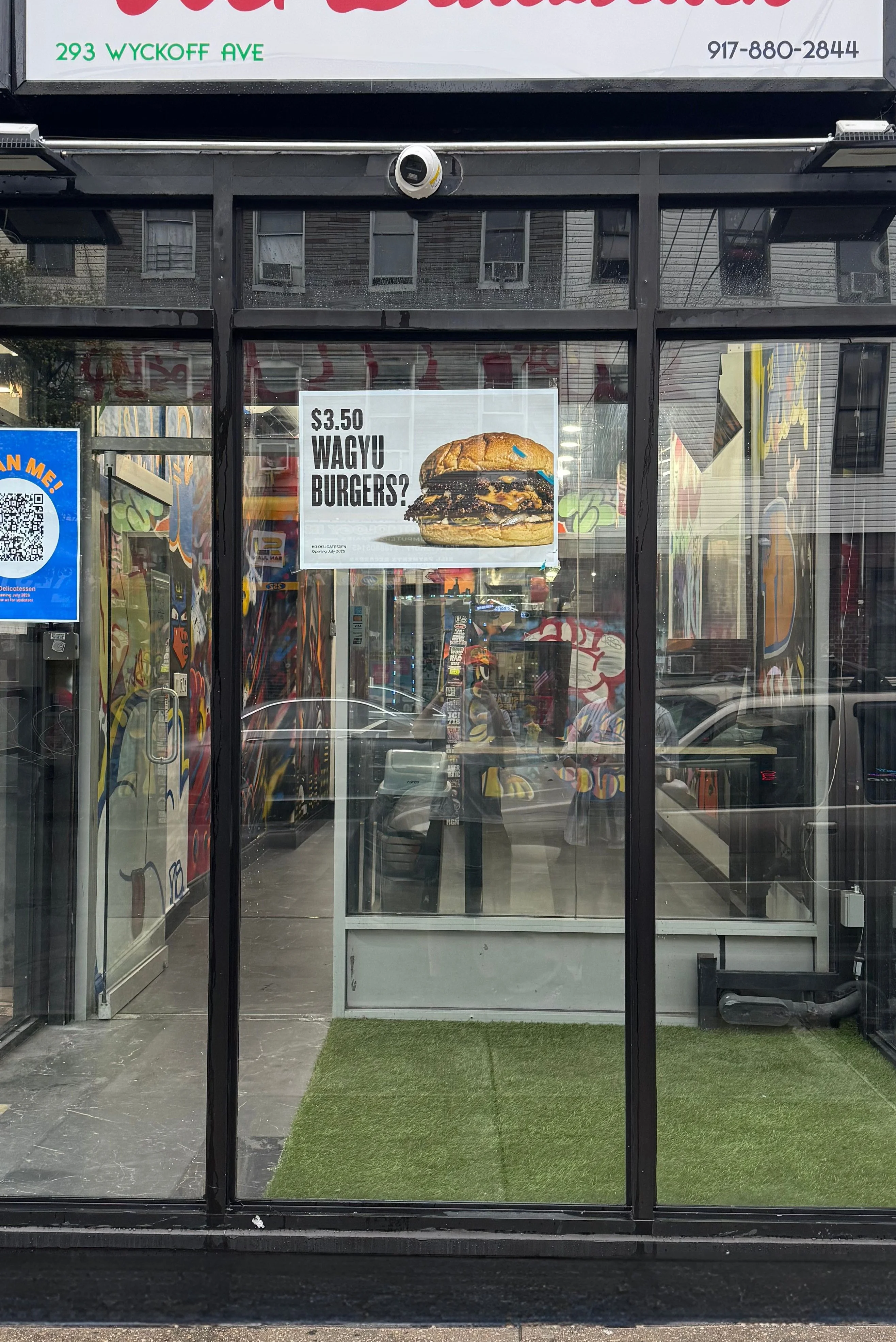 Exterior view of KG Delicatessen with a sign and promotional poster