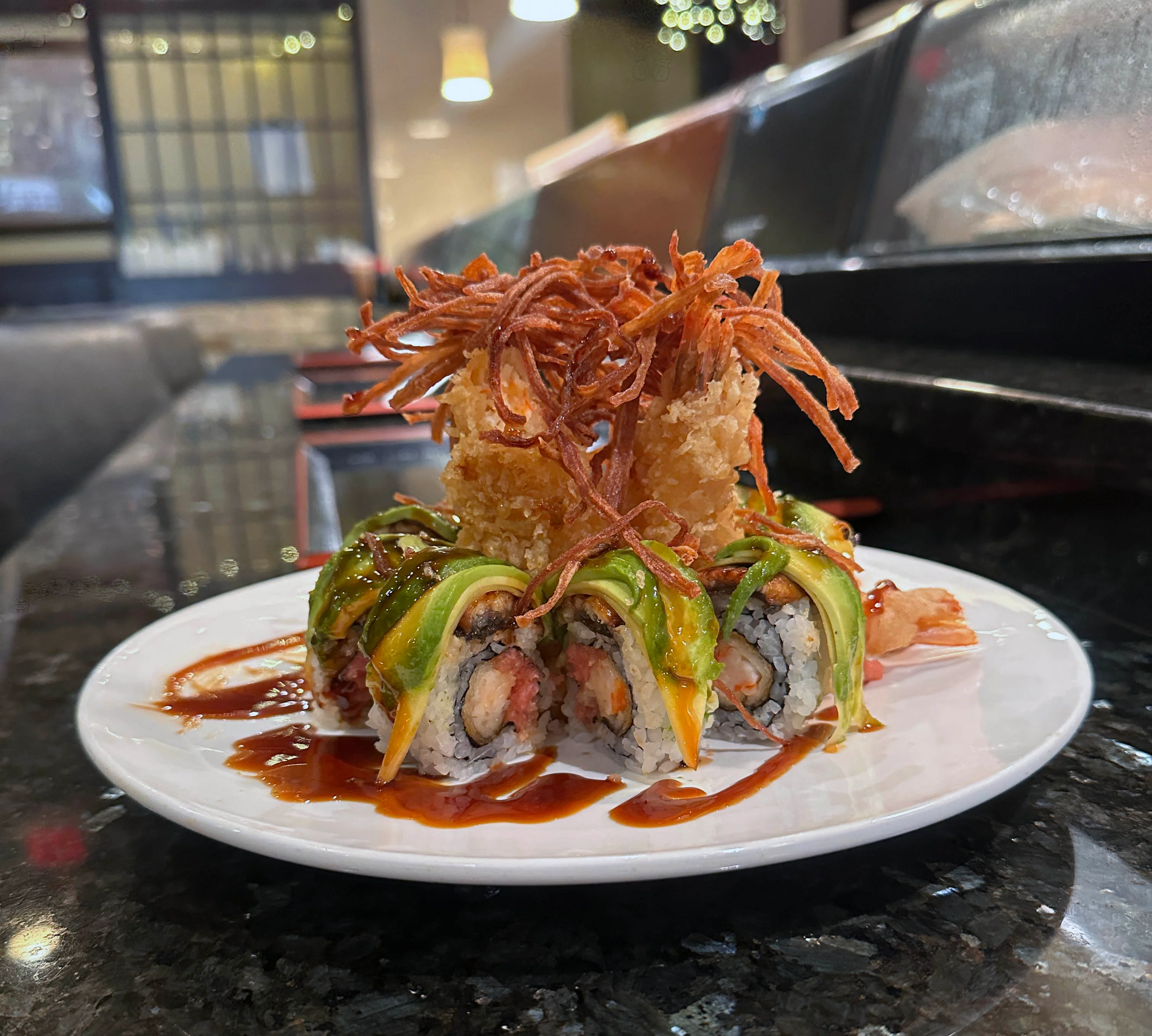 Specialty sushi roll topped with avocado and crispy onion at the sushi bar at Mahzu East Windsor