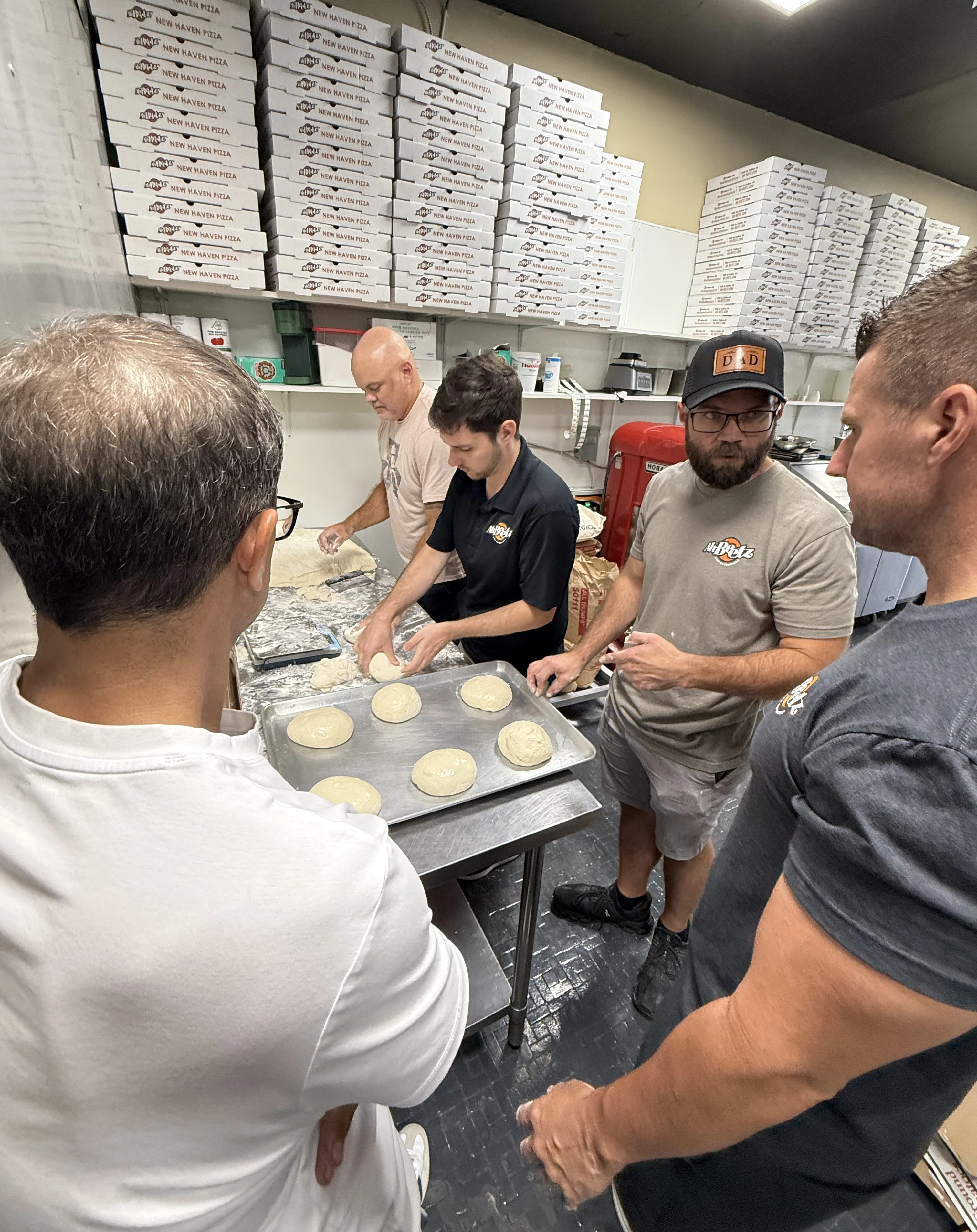 An employee swirling sauce on a pizza