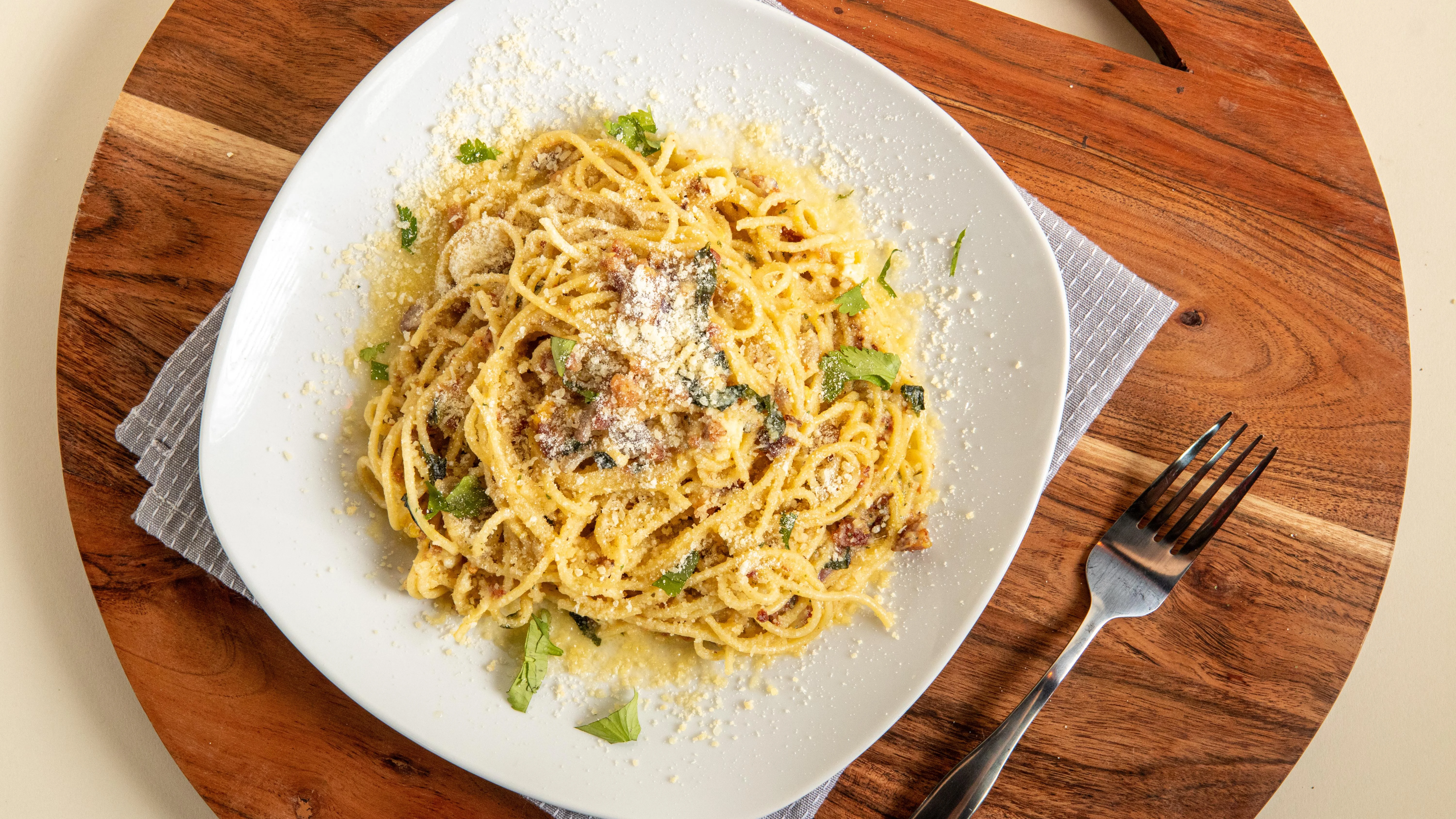 A plate of spaghetti topped with herbs and cheese, garnished for an appealing presentation.