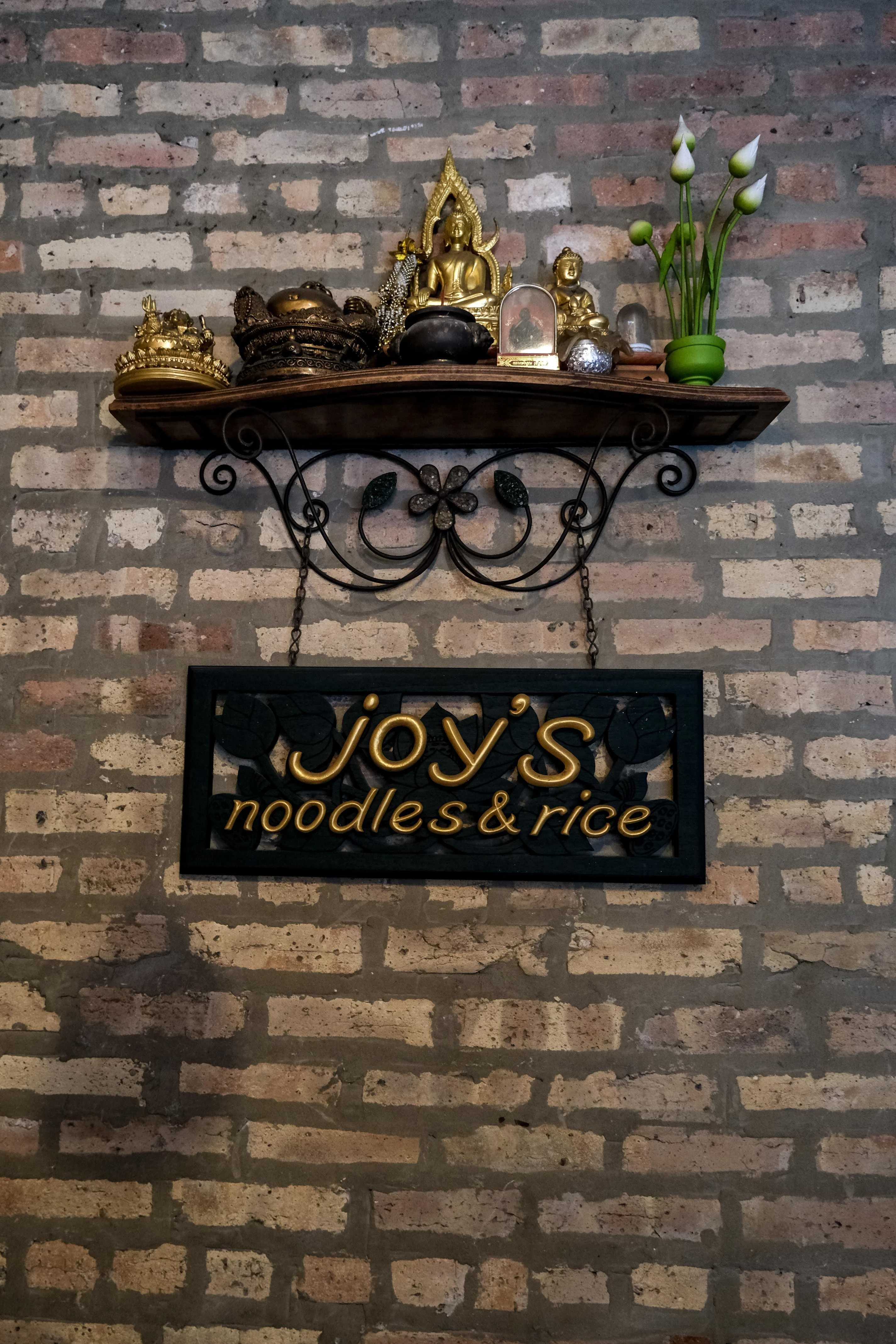 Charming restaurant sign for Joy's Noodles & Rice with decorative shelf