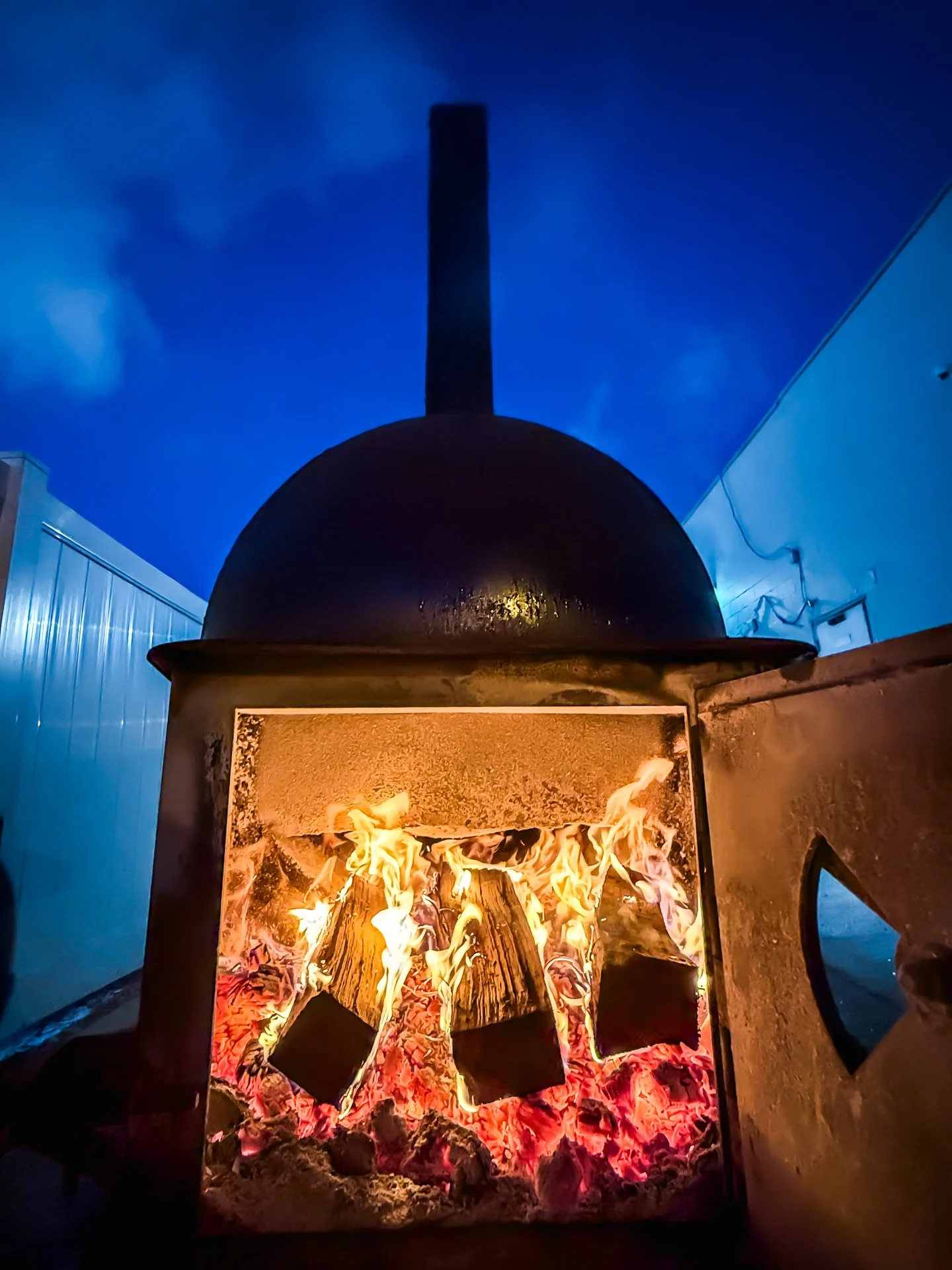 Wood-fired oven with flames and glowing embers