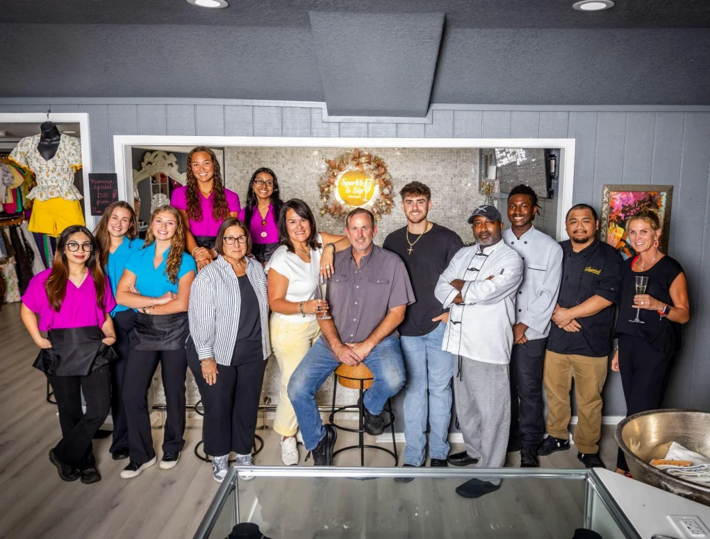Team photo in a stylish restaurant setting with jewelry display