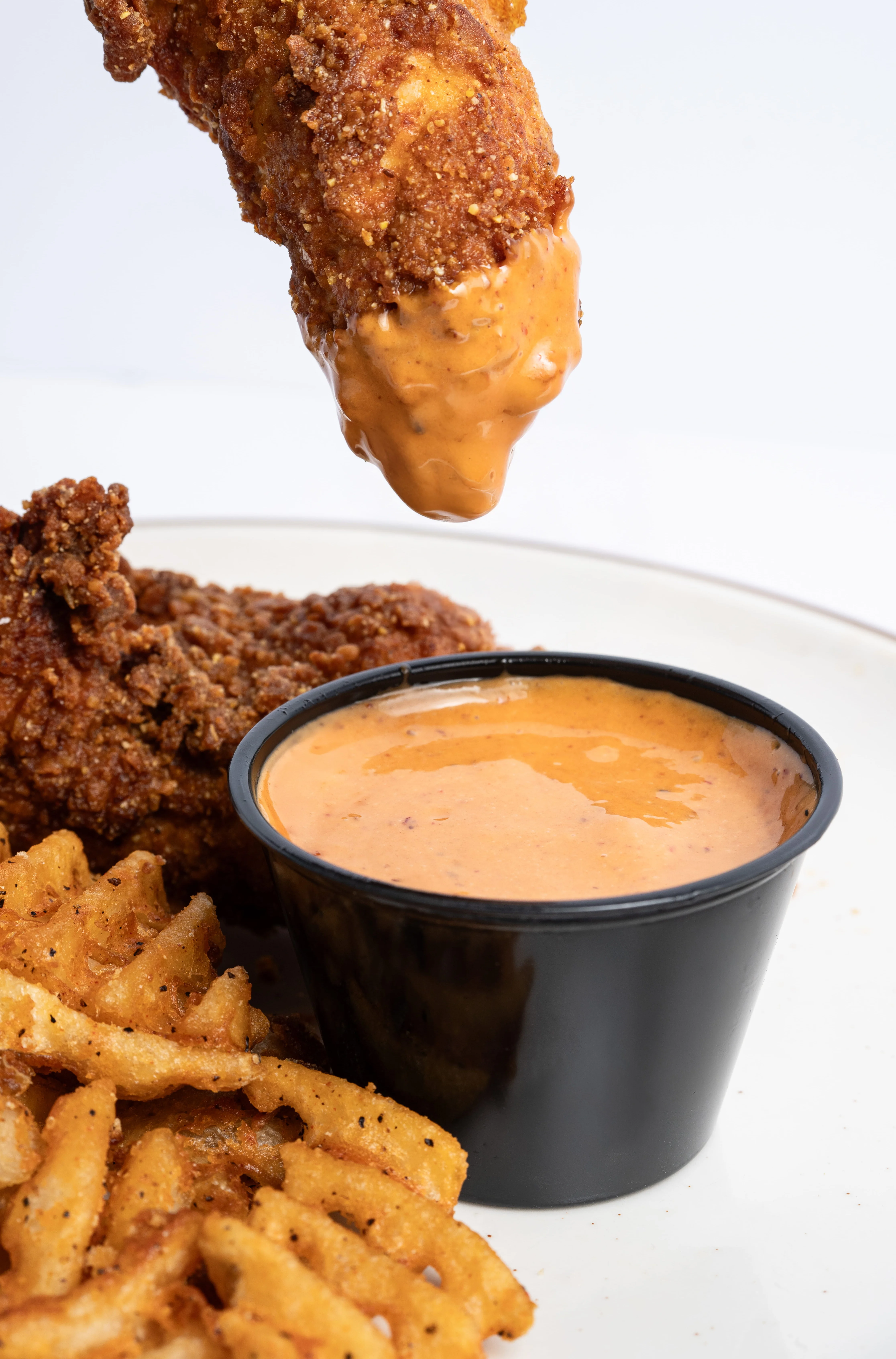 Woodstone Chicken & Waffle owner holding a plate of fried chicken and waffles at our San Luis Obispo restaurant on Foothill Blvd