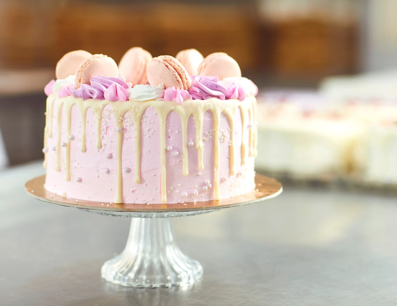 Pink drip cake with macarons and decorative frosting