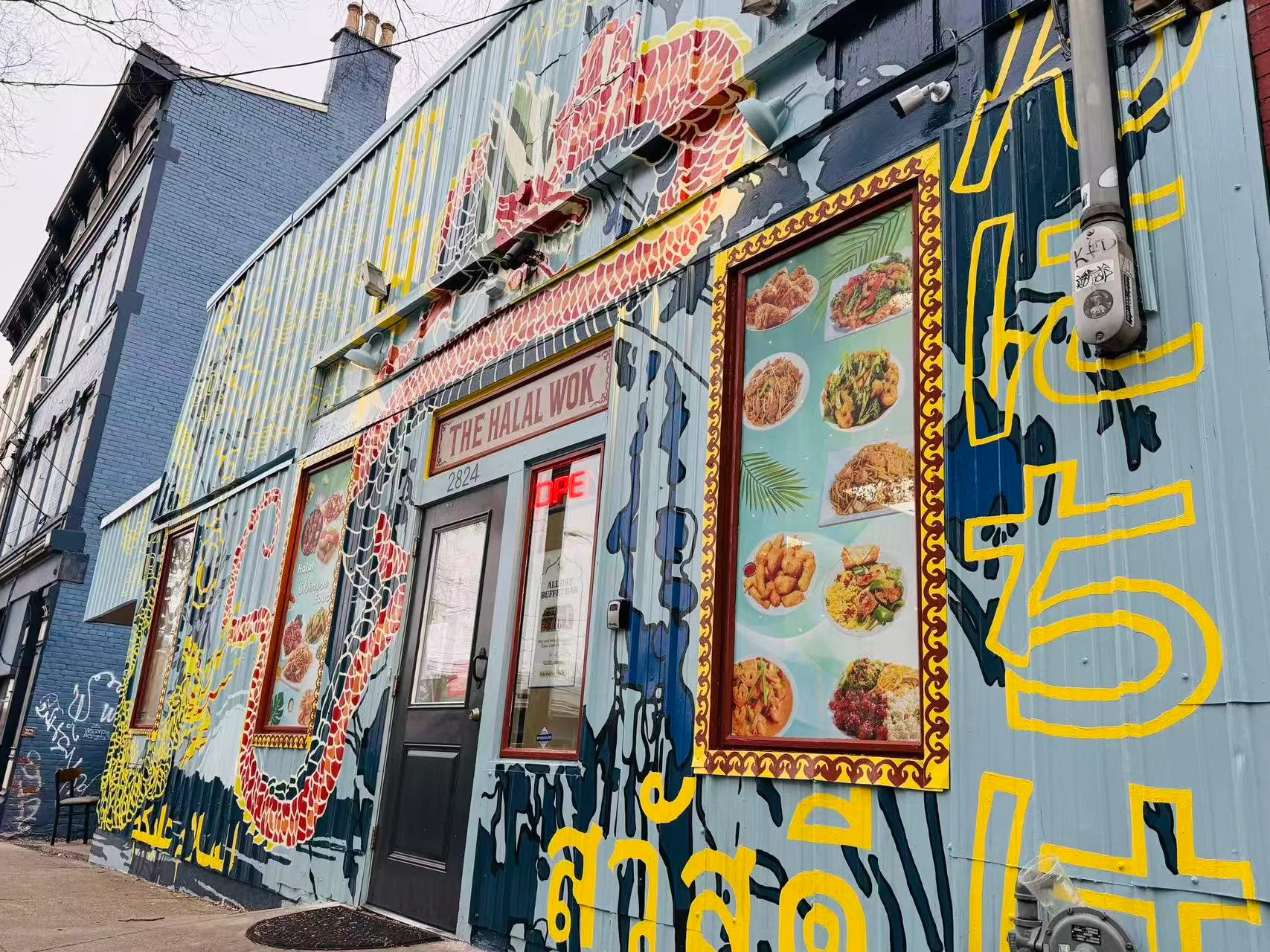 Colorful exterior of The Halal Wok restaurant with vibrant mural