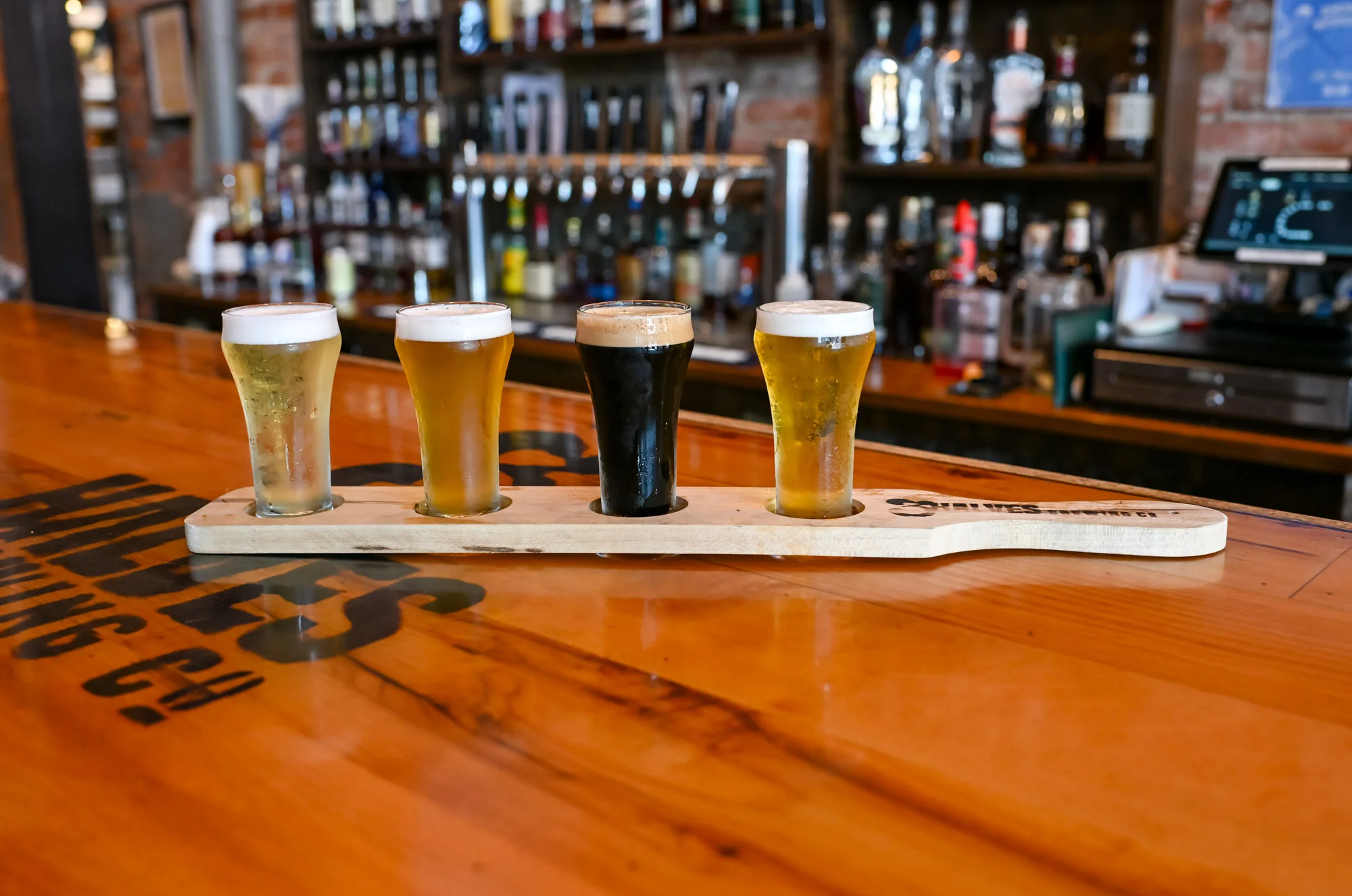 Craft beer flight with four distinct styles on a wooden paddle