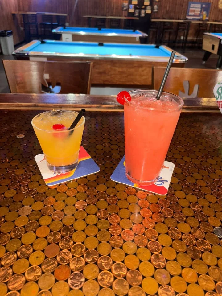 Colorful cocktails on a bar counter with pool tables in the background