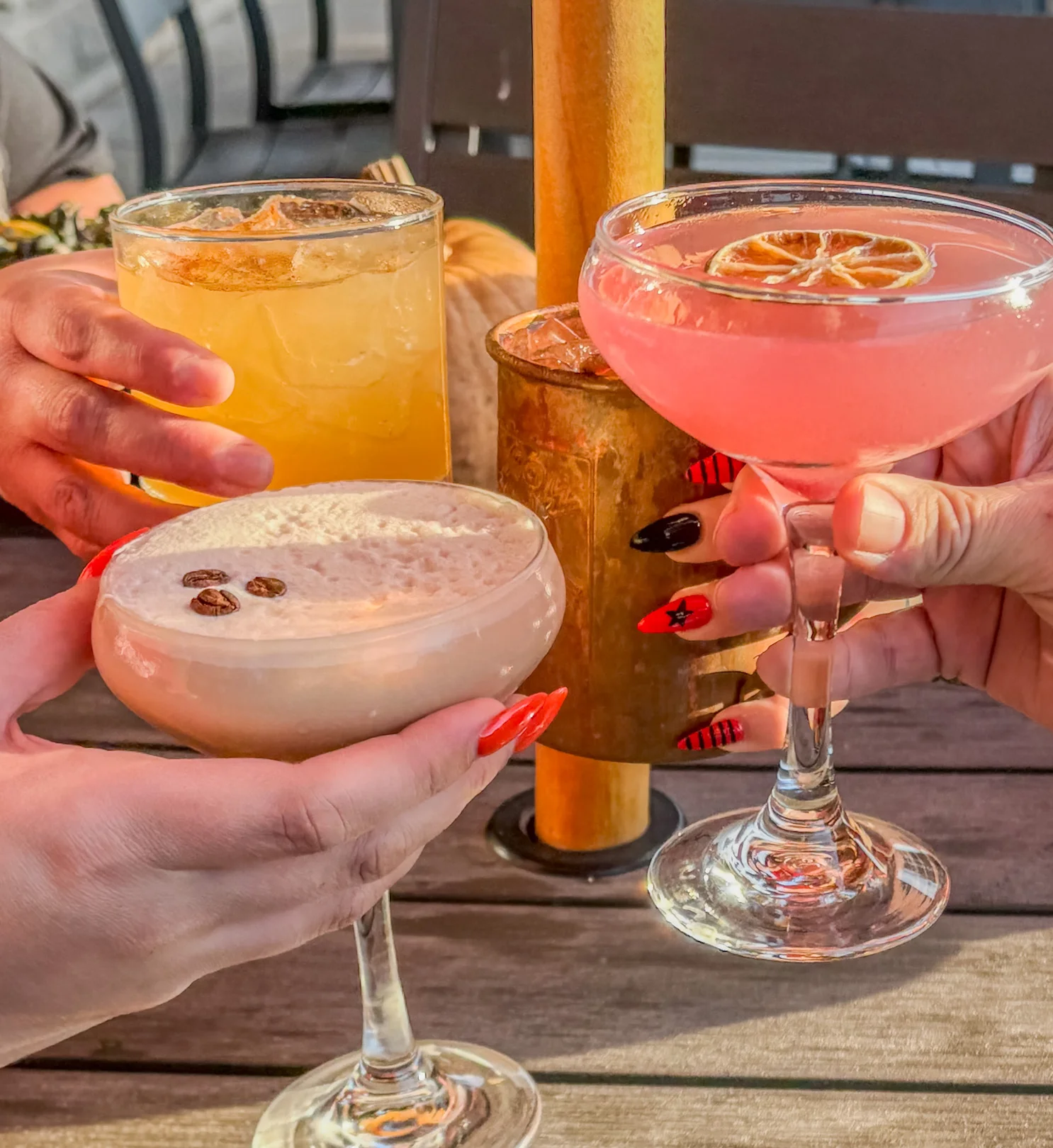 Colorful cocktails being toasted at a lively outdoor bar