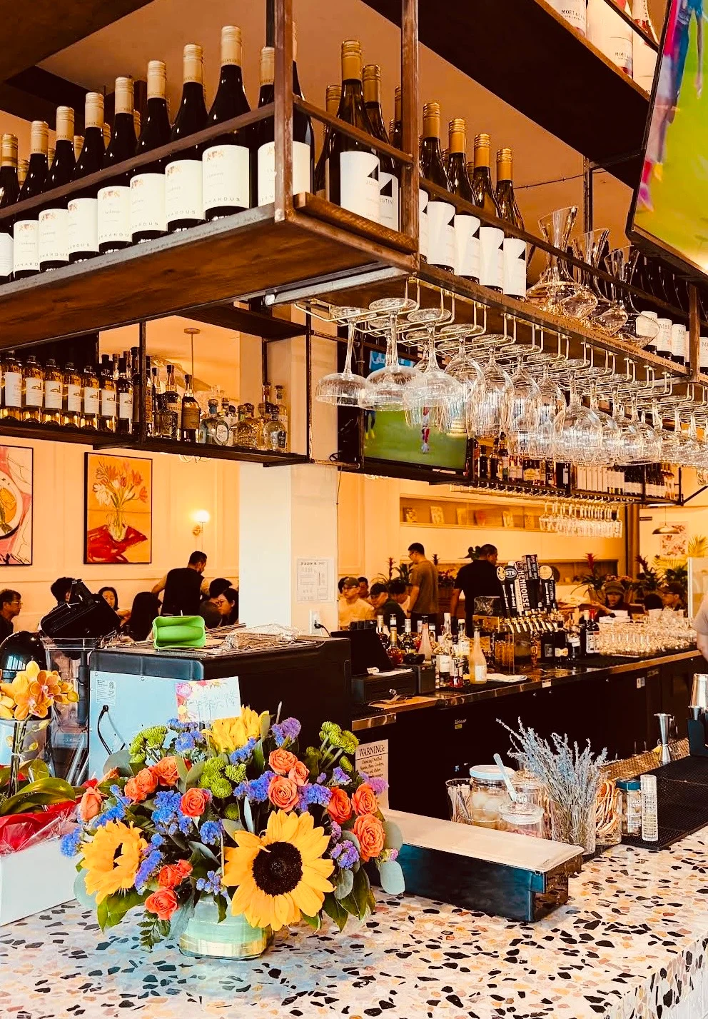 Vibrant restaurant bar with floral decor and wine bottles