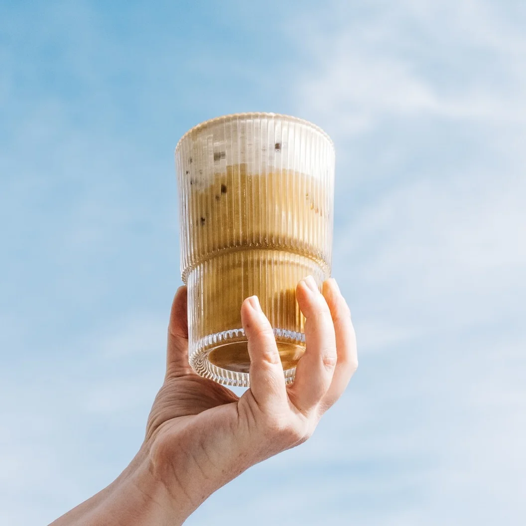 Iced coffee drink held against a blue sky