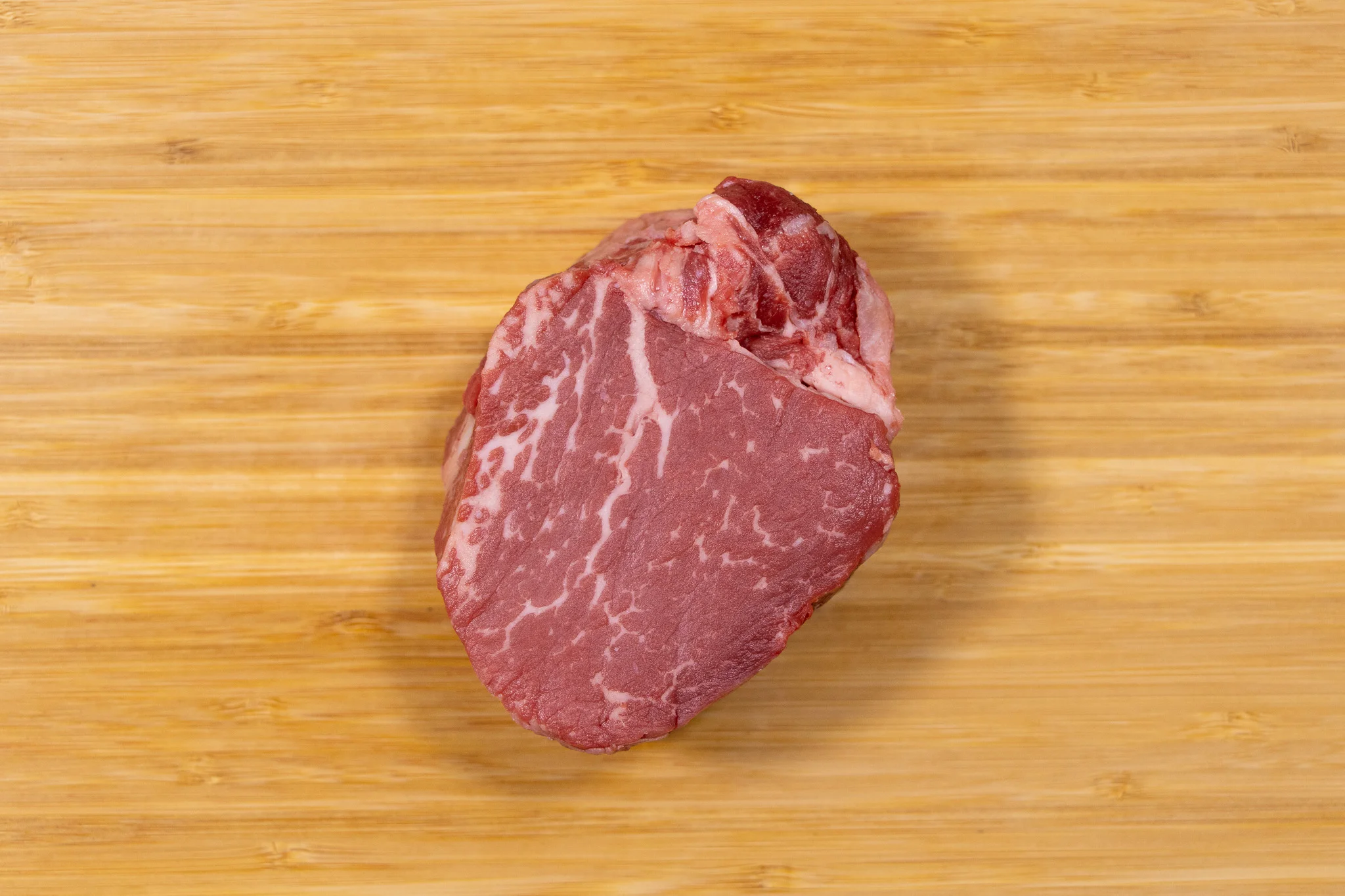 Raw ribeye steak on a wooden cutting board