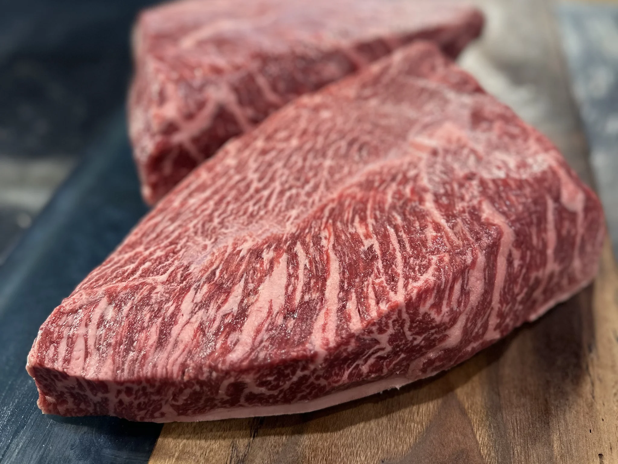 Close-up of marbled beef cuts on a wooden surface.
