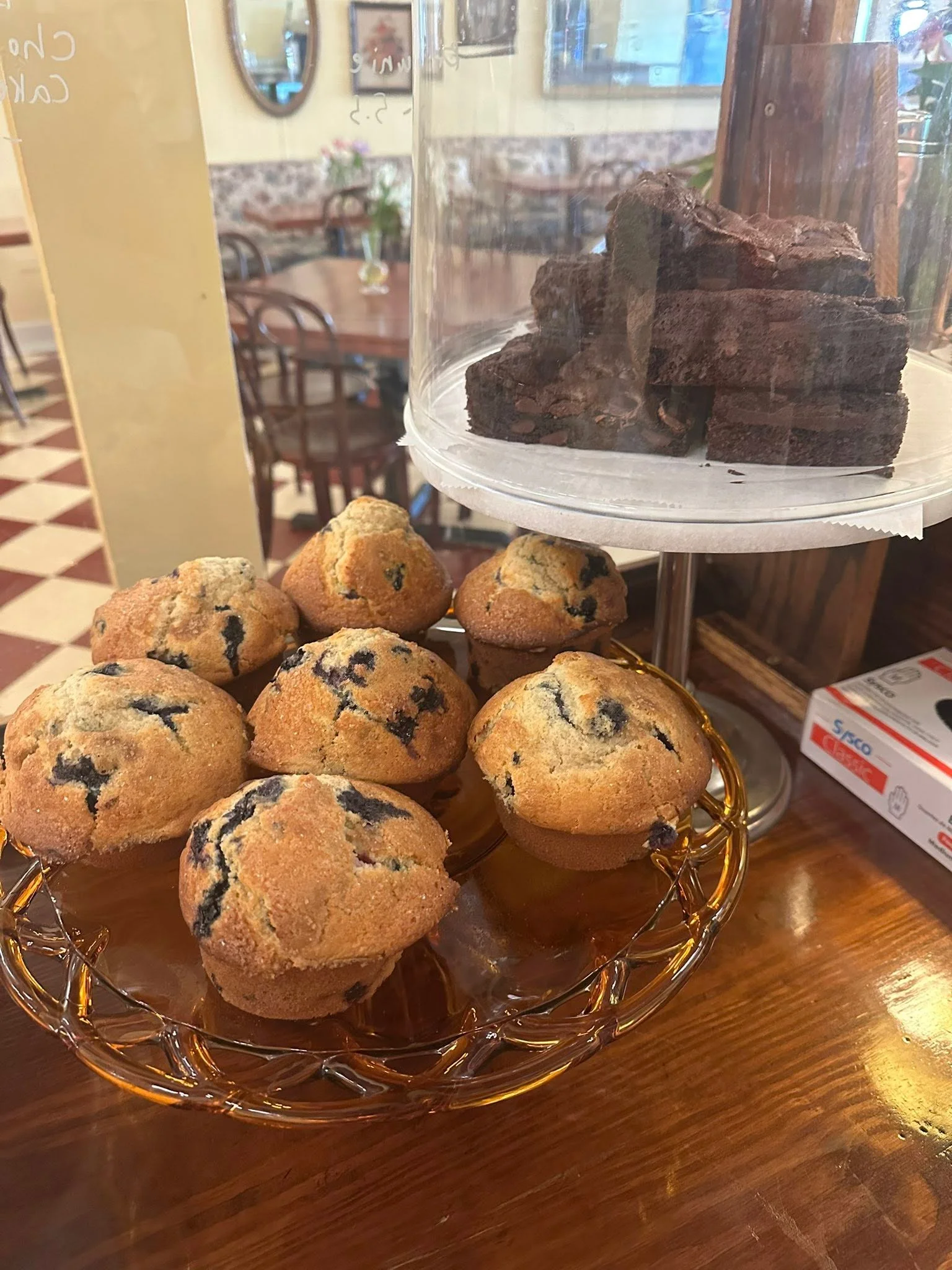 Freshly baked blueberry muffins on a glass display stand