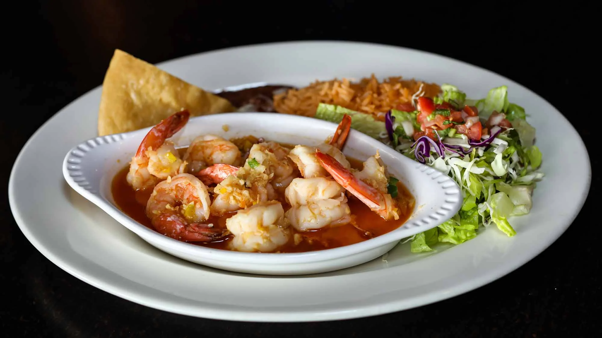 Shrimp enchiladas with rice and salad on a white plate