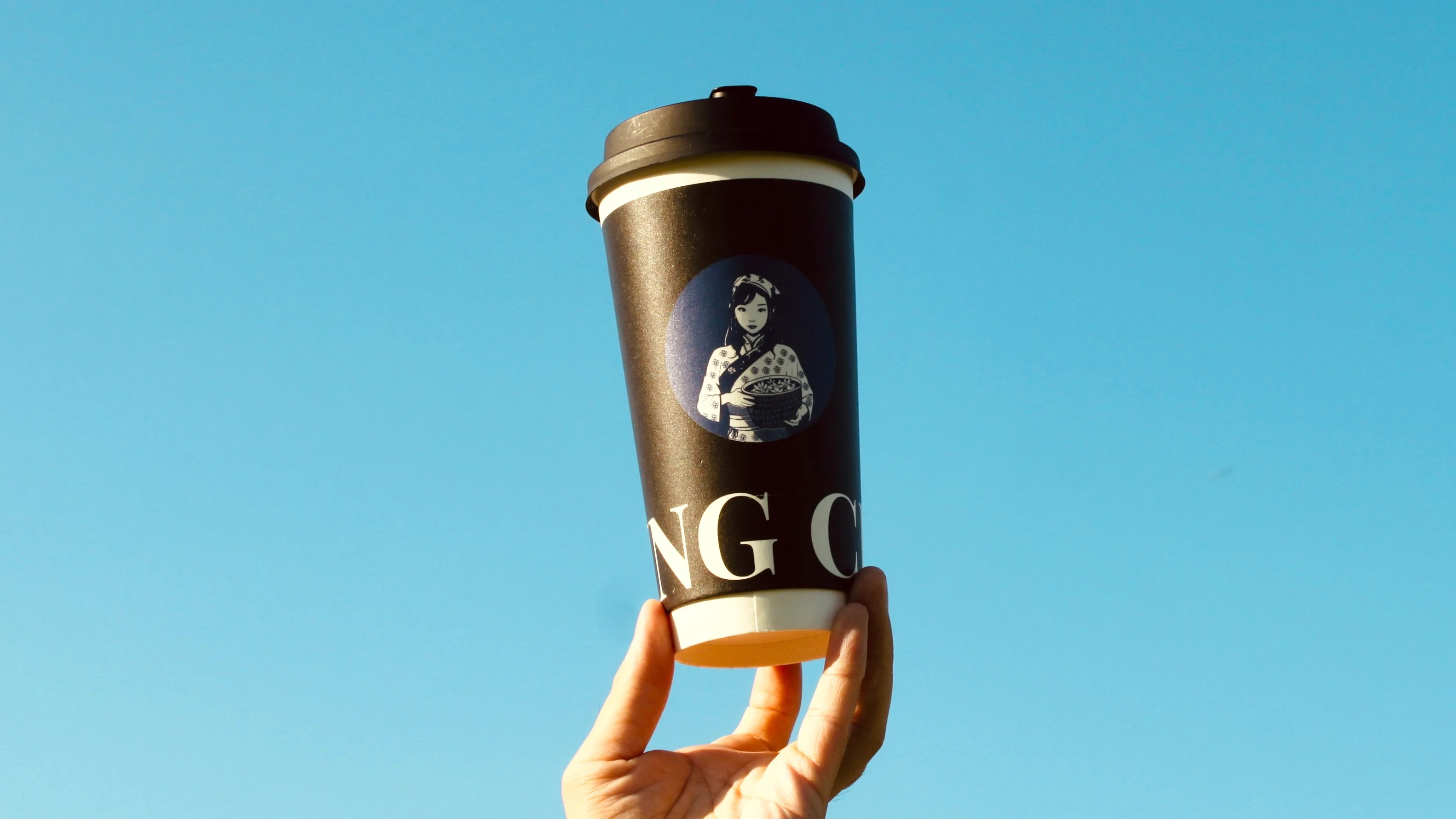 Coffee cup with Japanese design against a blue sky