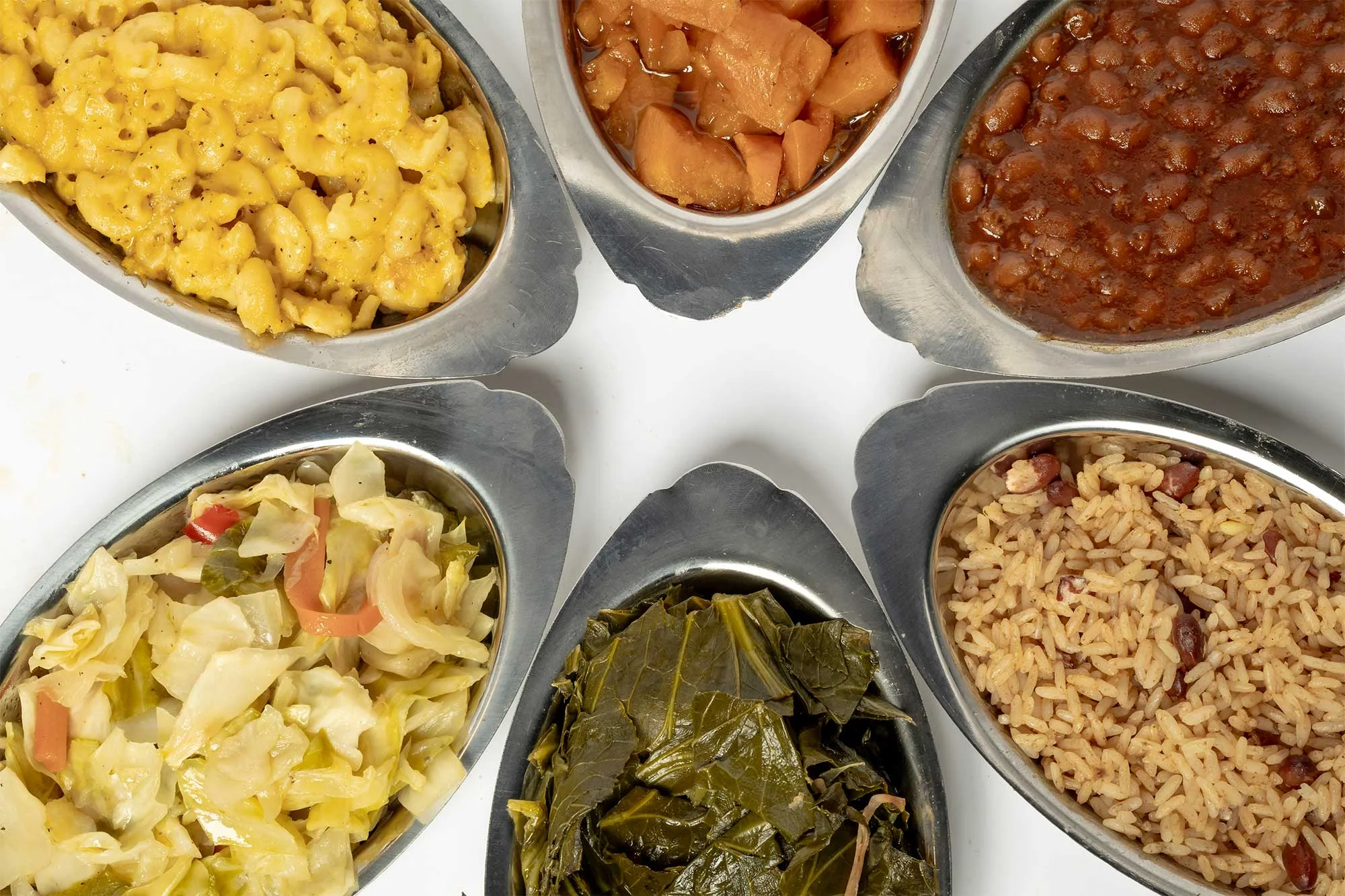 Delicious side dishes includes cabbage, greens, rice and beans, yams