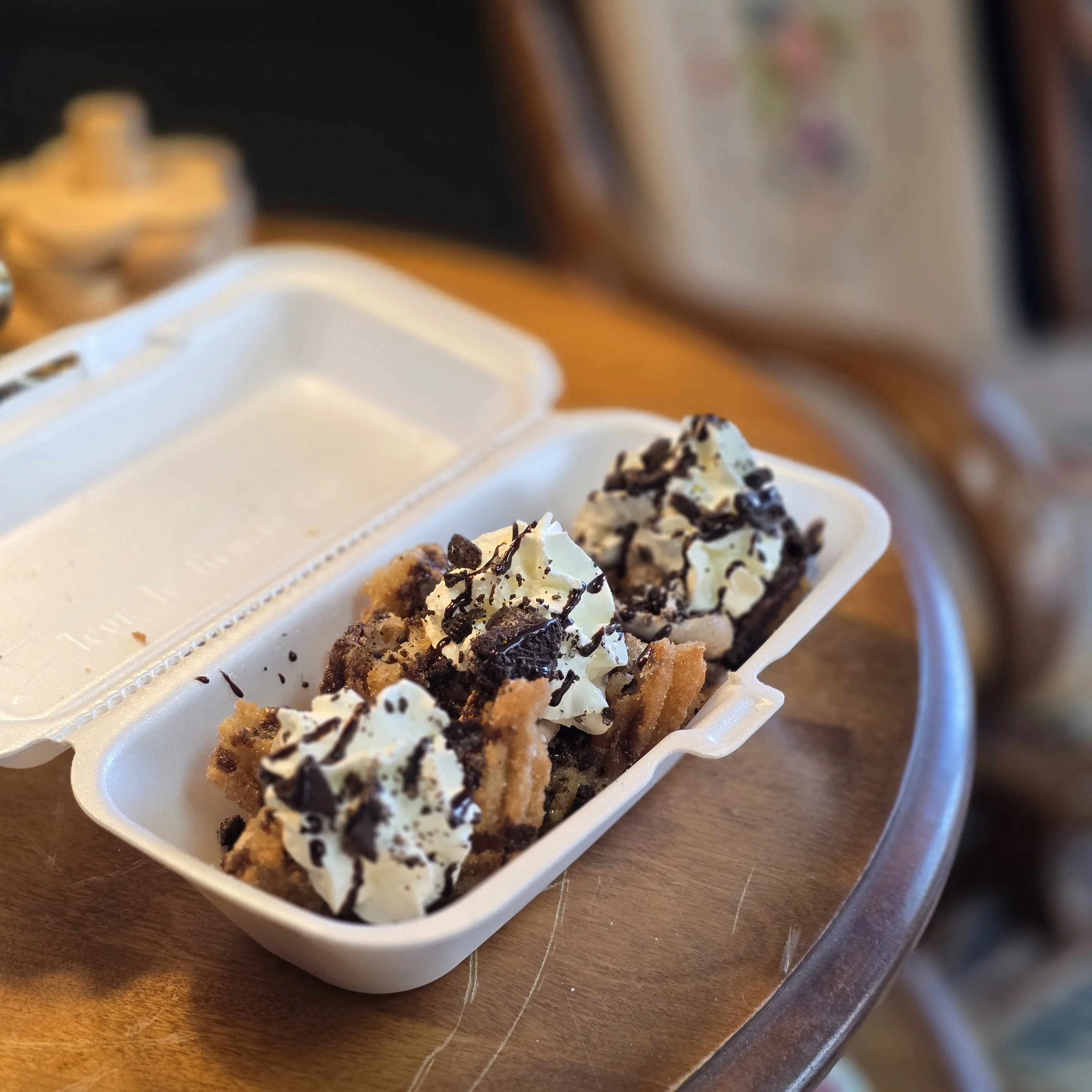 Churros topped with whipped cream and chocolate crumbs