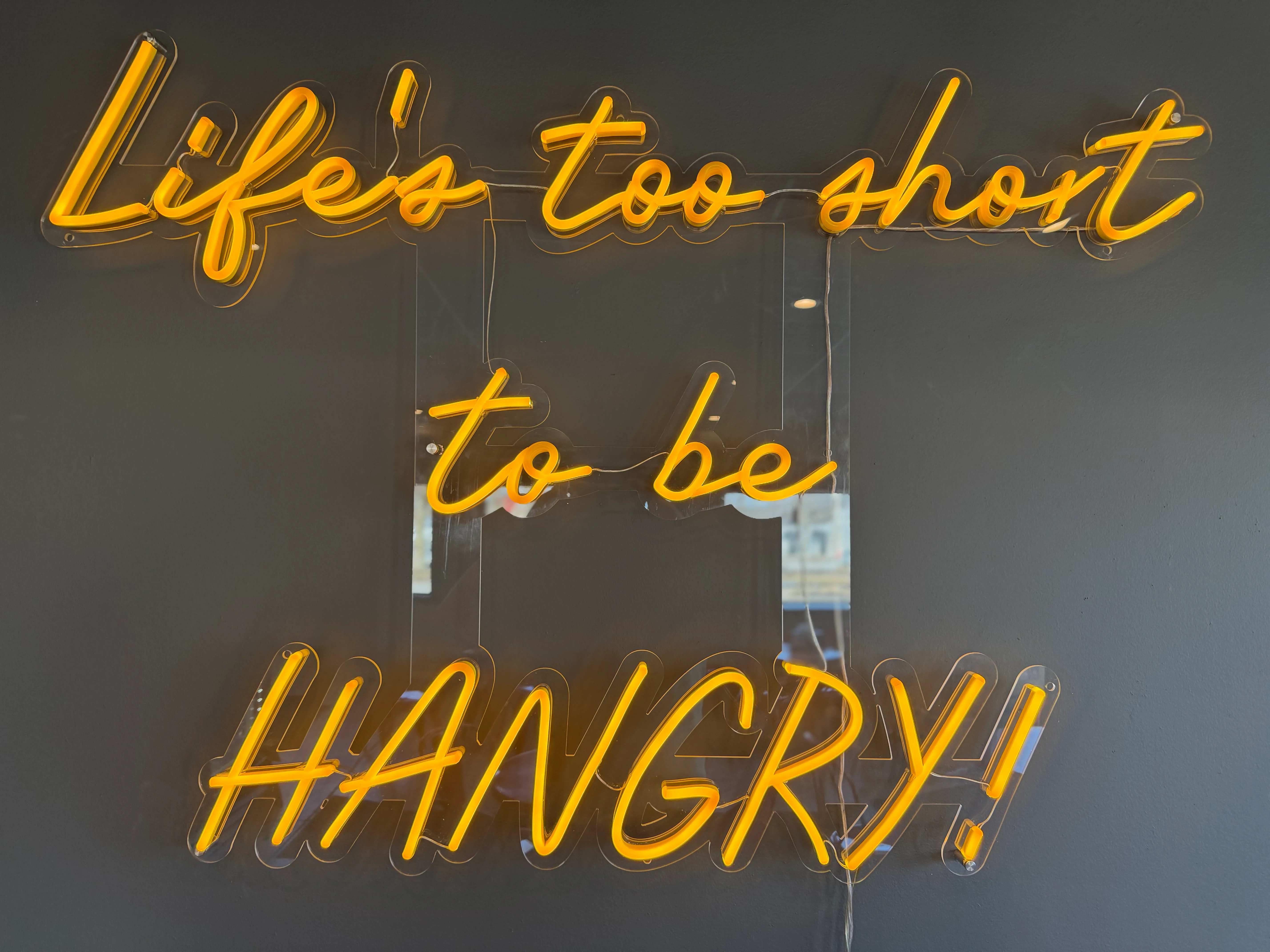 Neon sign reading 'Life's too short to be HANGRY!' in a restaurant