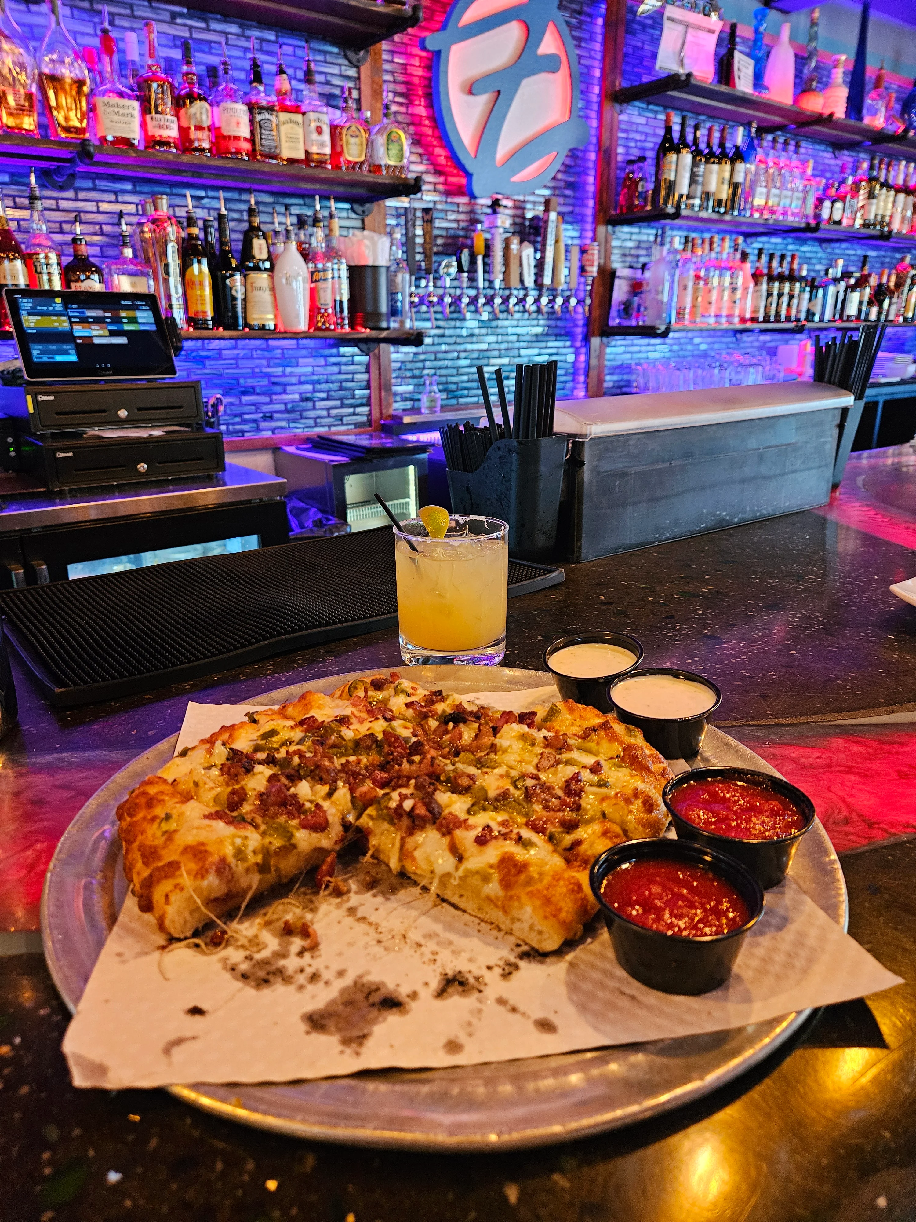 Loaded pizza with bacon and cheese at a vibrant bar