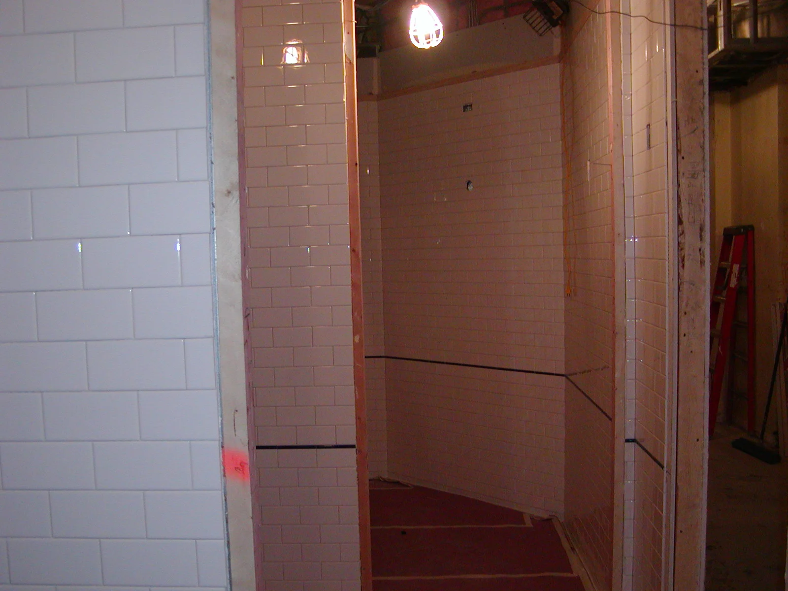 Under-construction restaurant space with tiled walls and exposed lighting