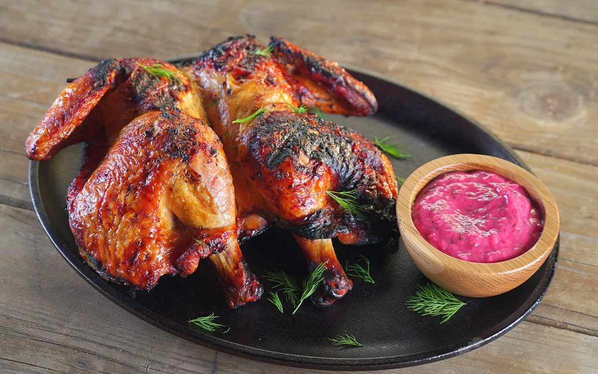 Grilled chicken served with a colorful dipping sauce, garnished with fresh herbs.