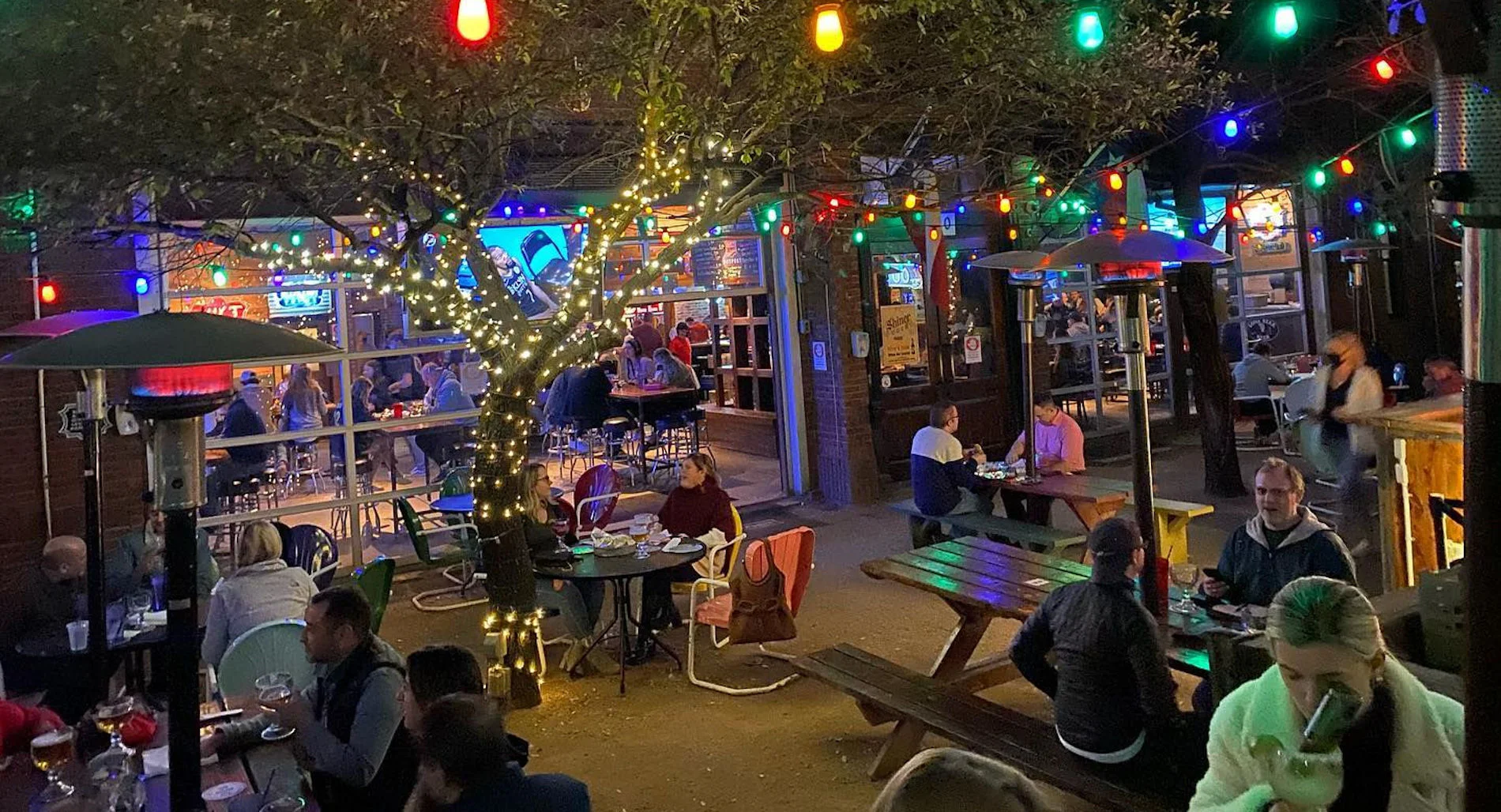 Lively outdoor restaurant patio with string lights and tree-lined dining area