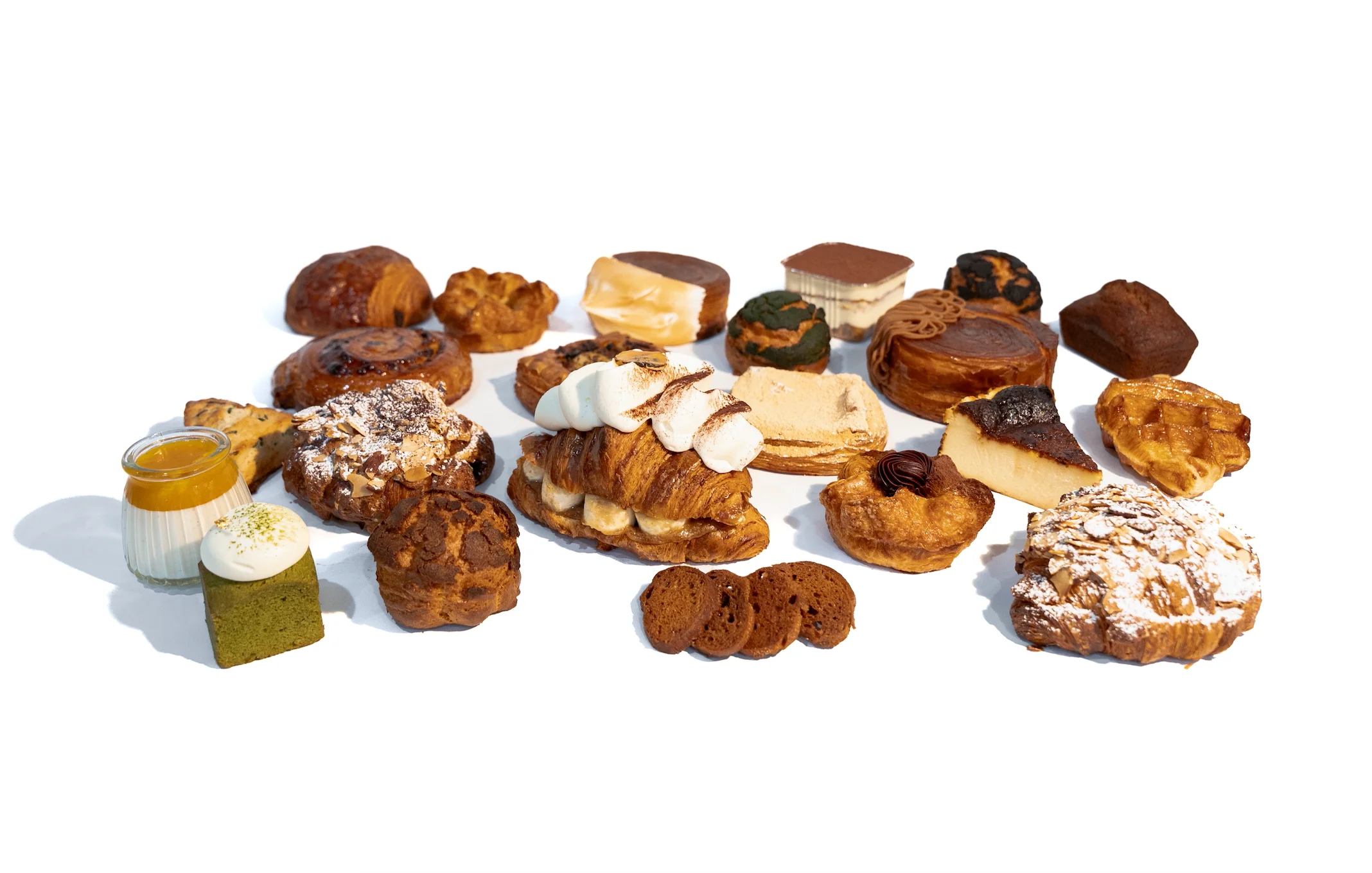 An assortment of various pastries and desserts including croissants, cakes, and sweet treats arranged on a white background.