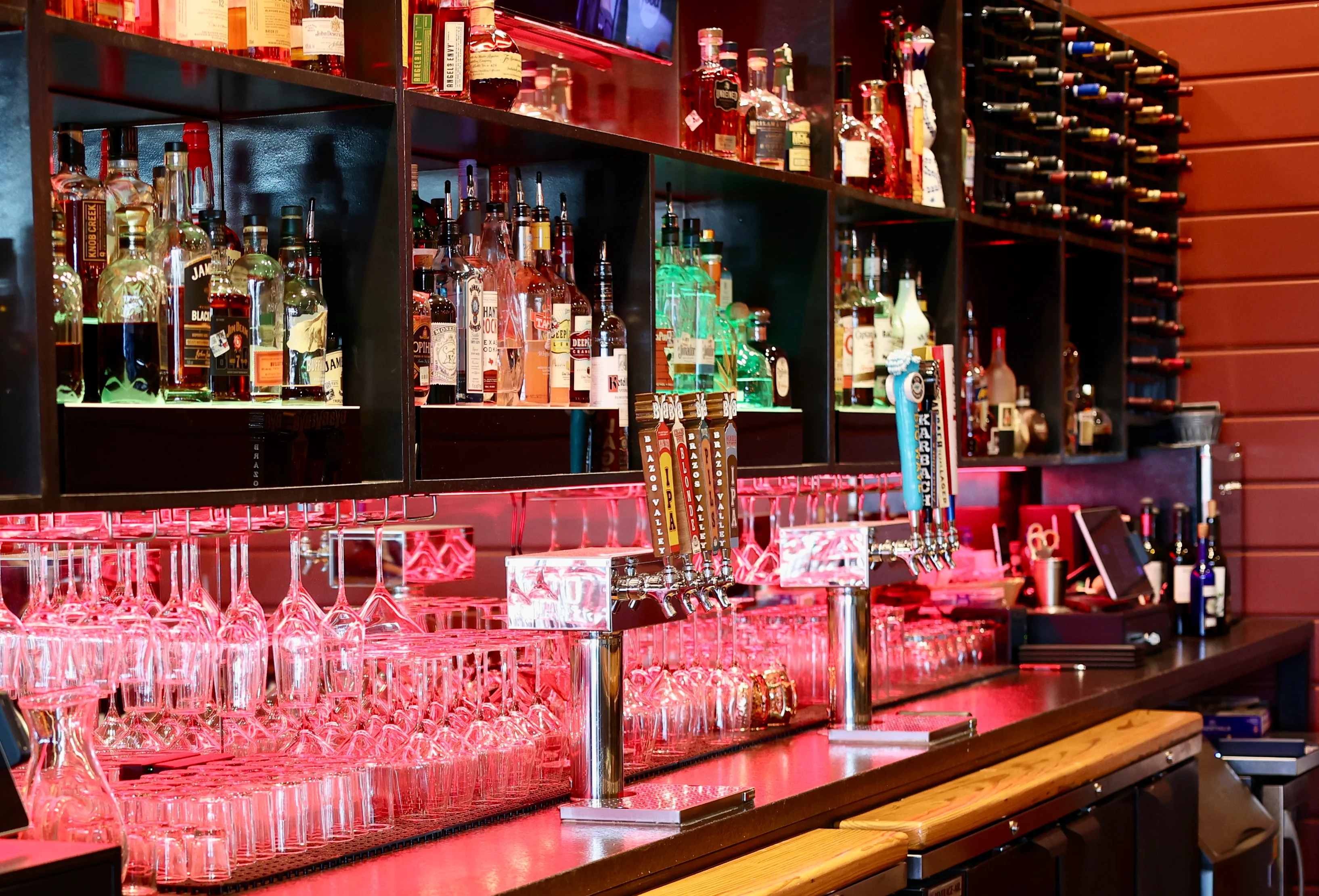 Modern bar counter with colorful liquor bottles and glassware
