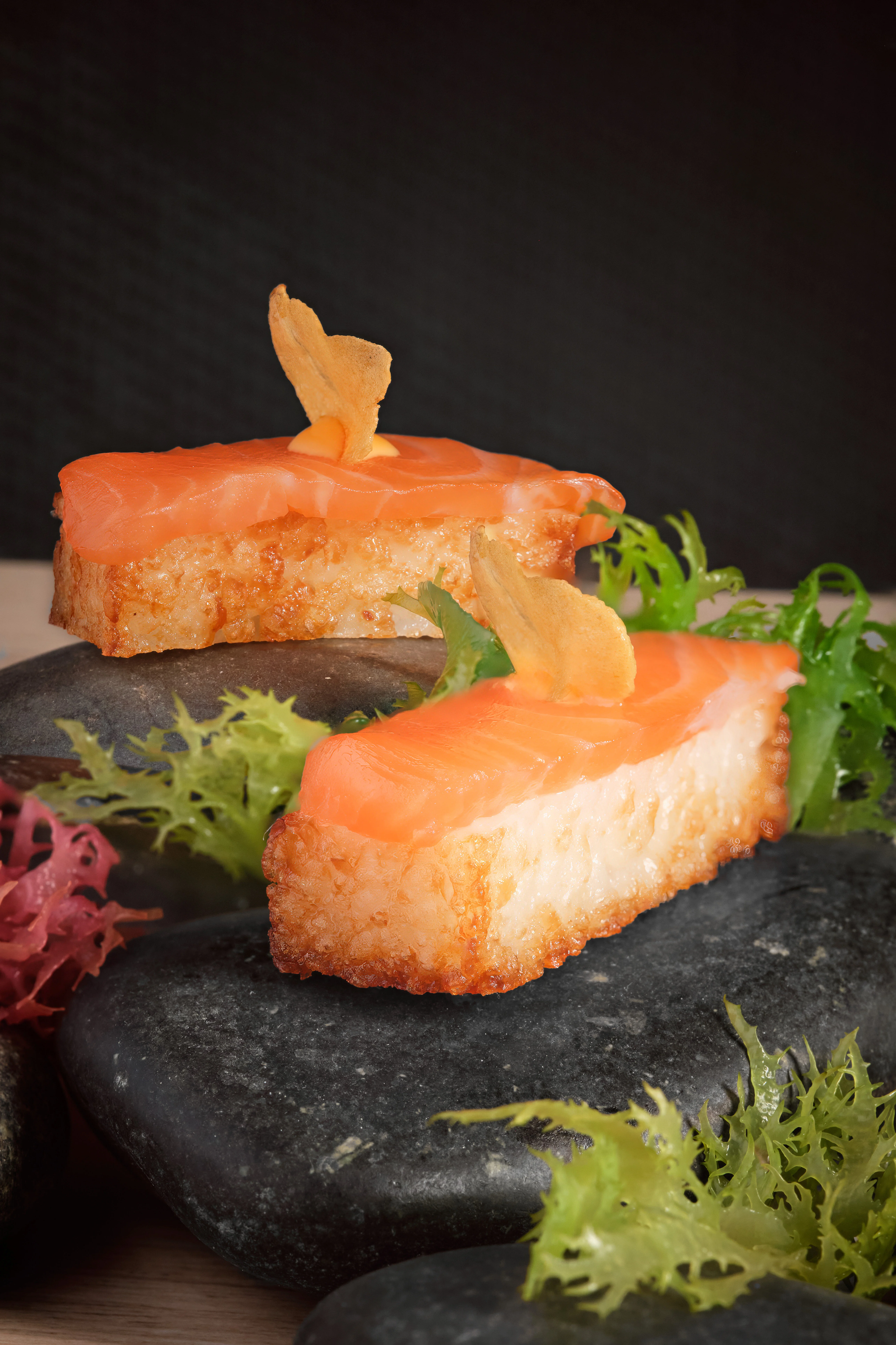 Japanese sushi with salmon on crispy rice served on black stones