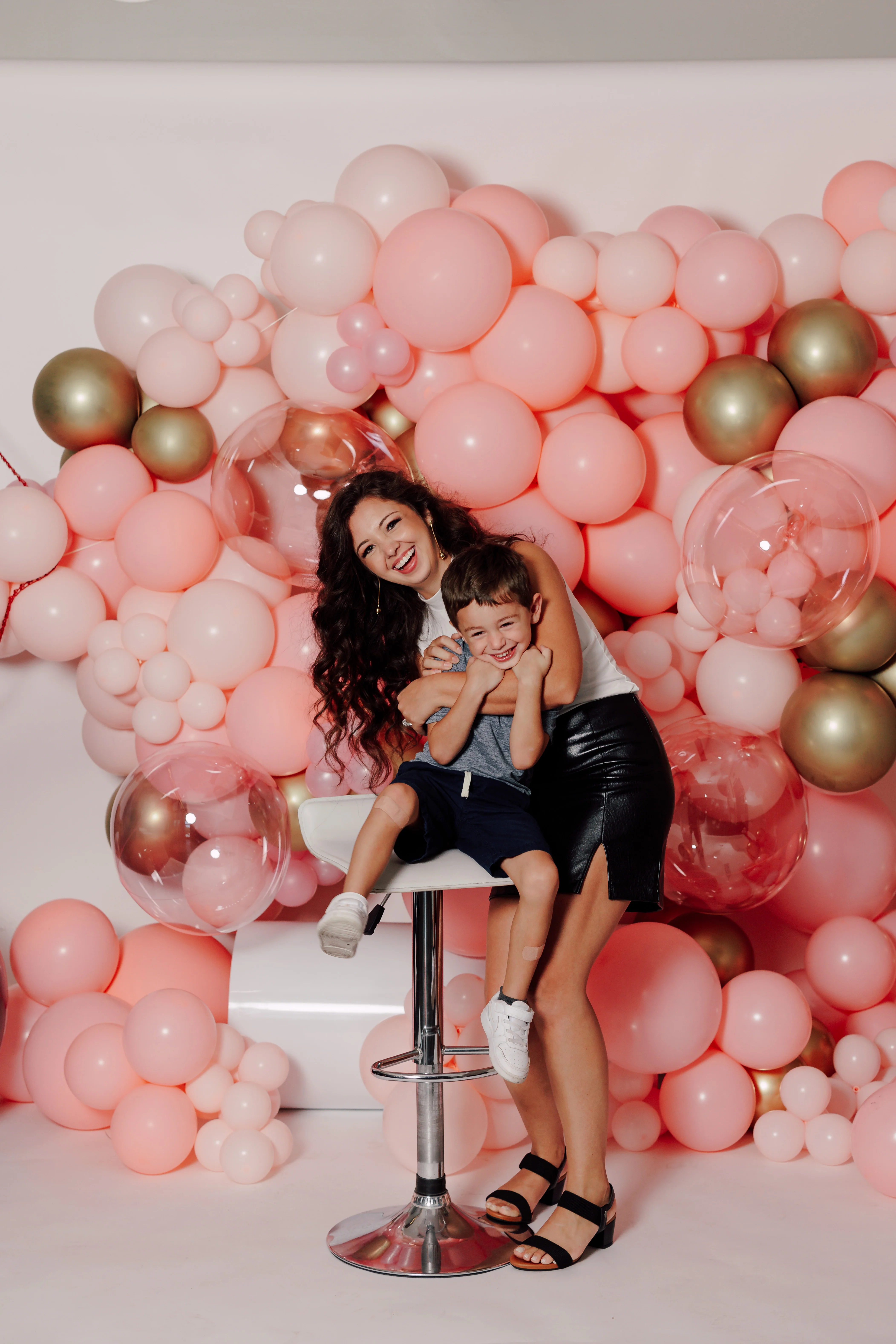 Happy mother and son posing in front of a colorful balloon backdrop