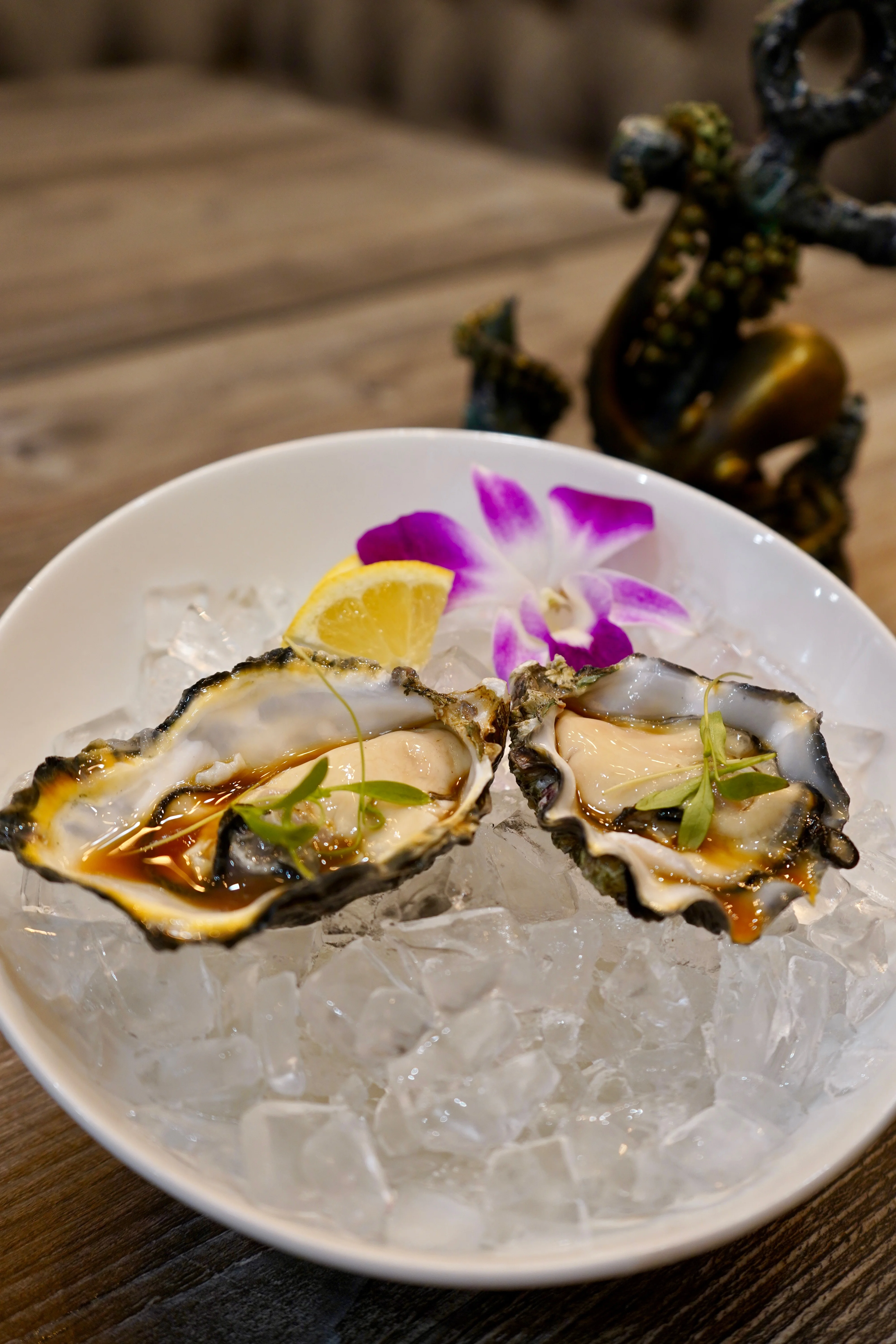 Plated oysters on ice with lemon and edible flowers