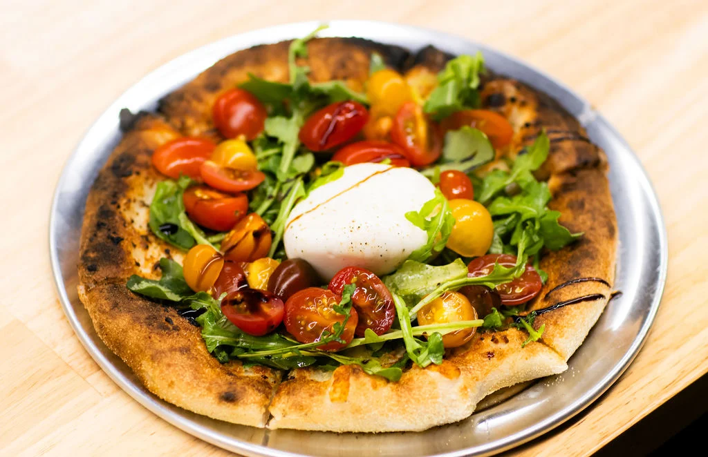 Burrata pizza topped with fresh tomatoes and arugula